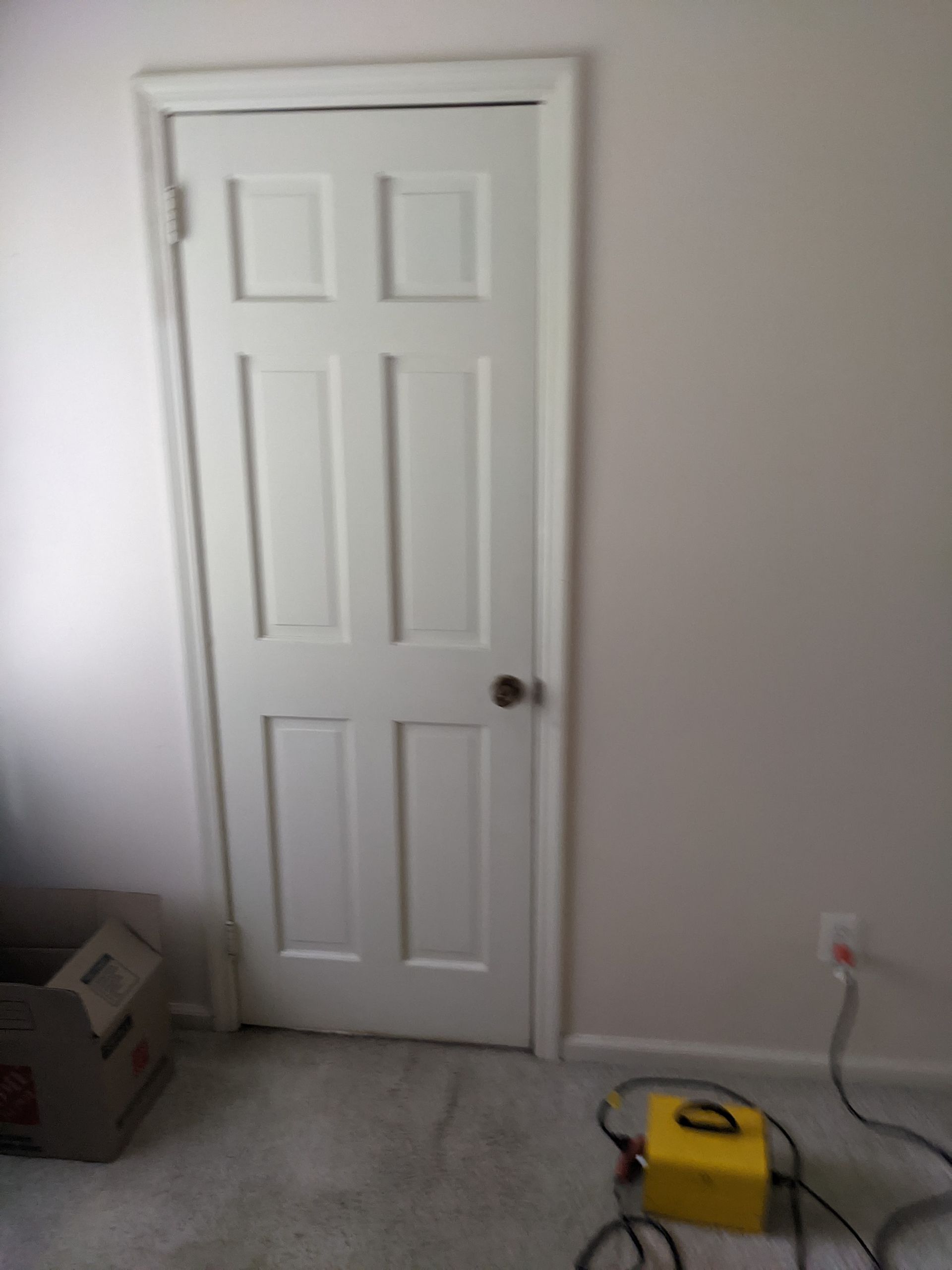 A white door is sitting in a room next to a yellow box.