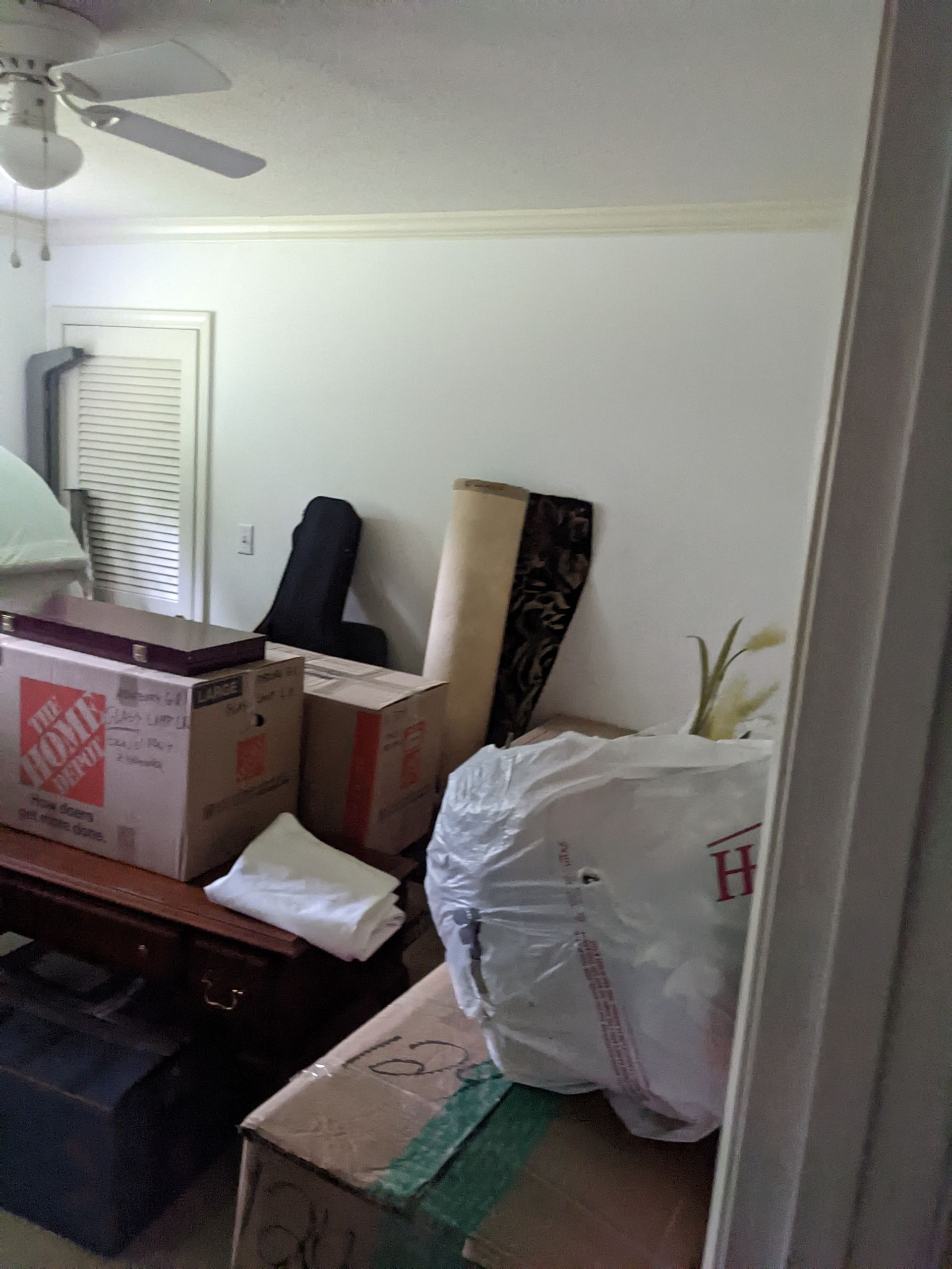 A room filled with boxes and a ceiling fan