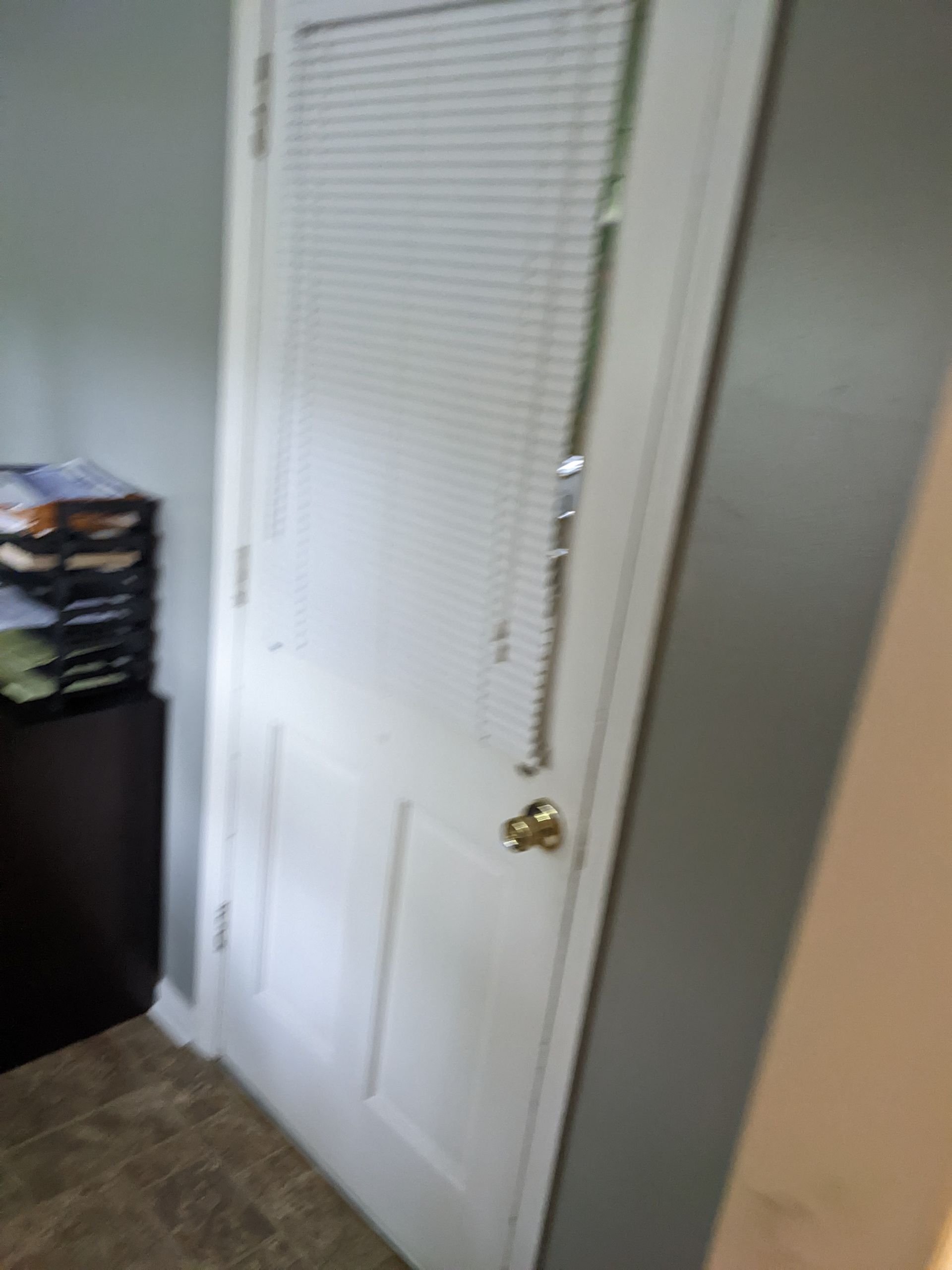 A white door with blinds on it is in a room.