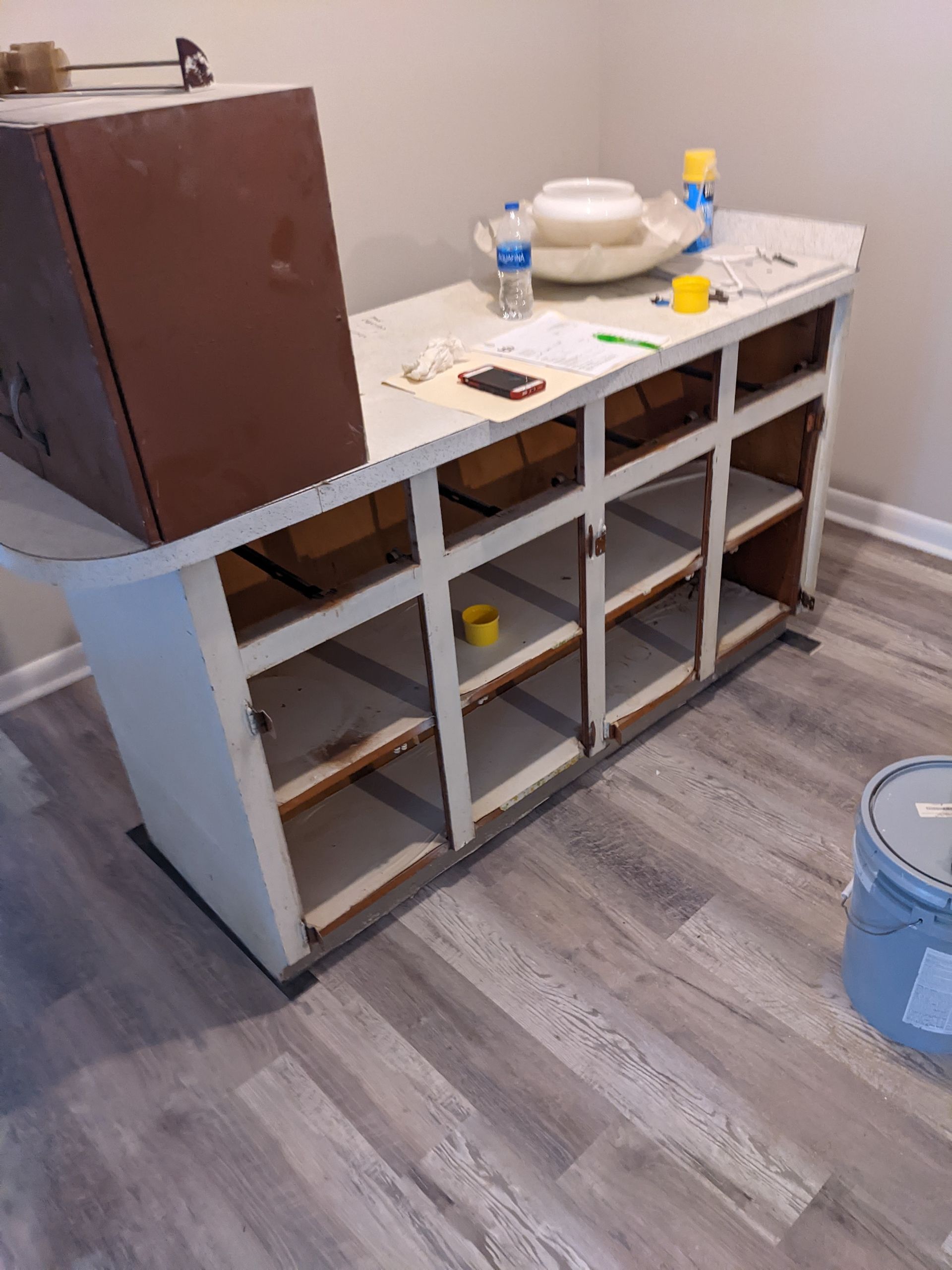 A room with a table and a bucket of paint on the floor.