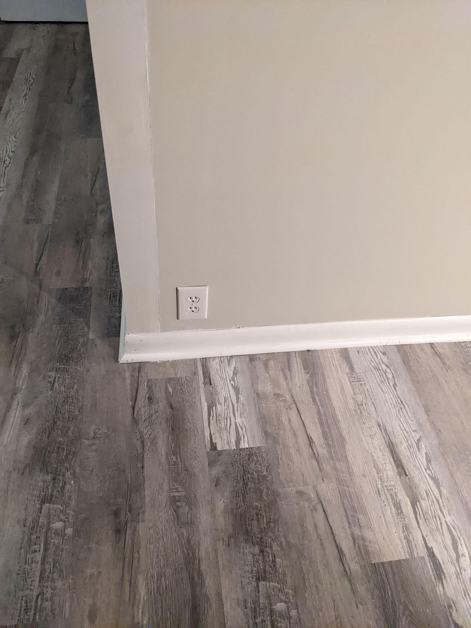 A close up of a wooden floor in a room with a wall.