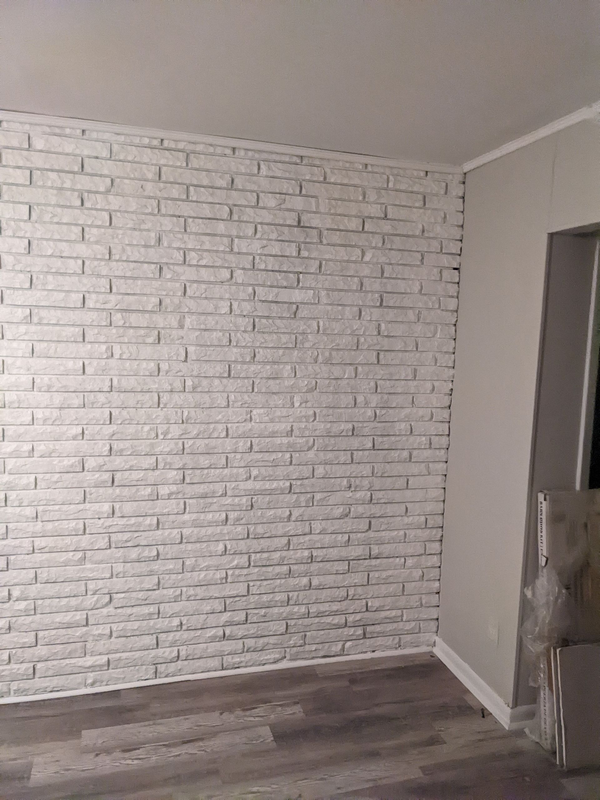 A room with a white brick wall and a wooden floor.