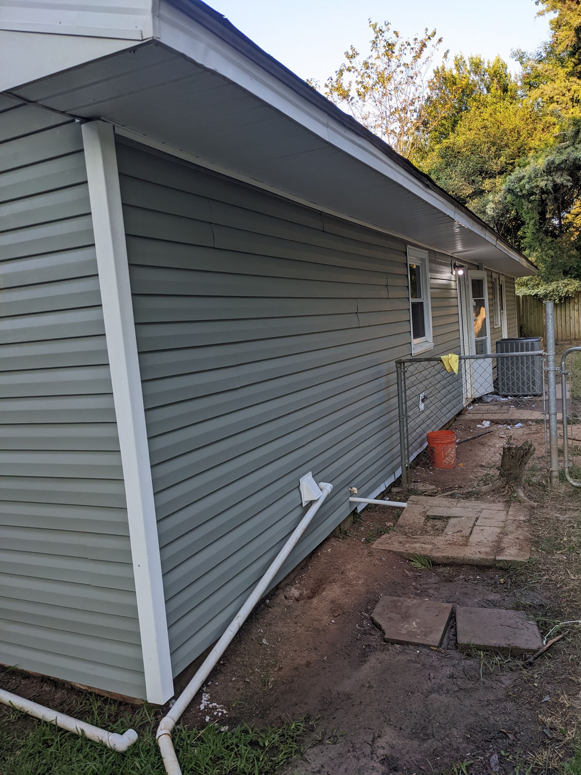 A house with a green siding and white trim is being remodeled.