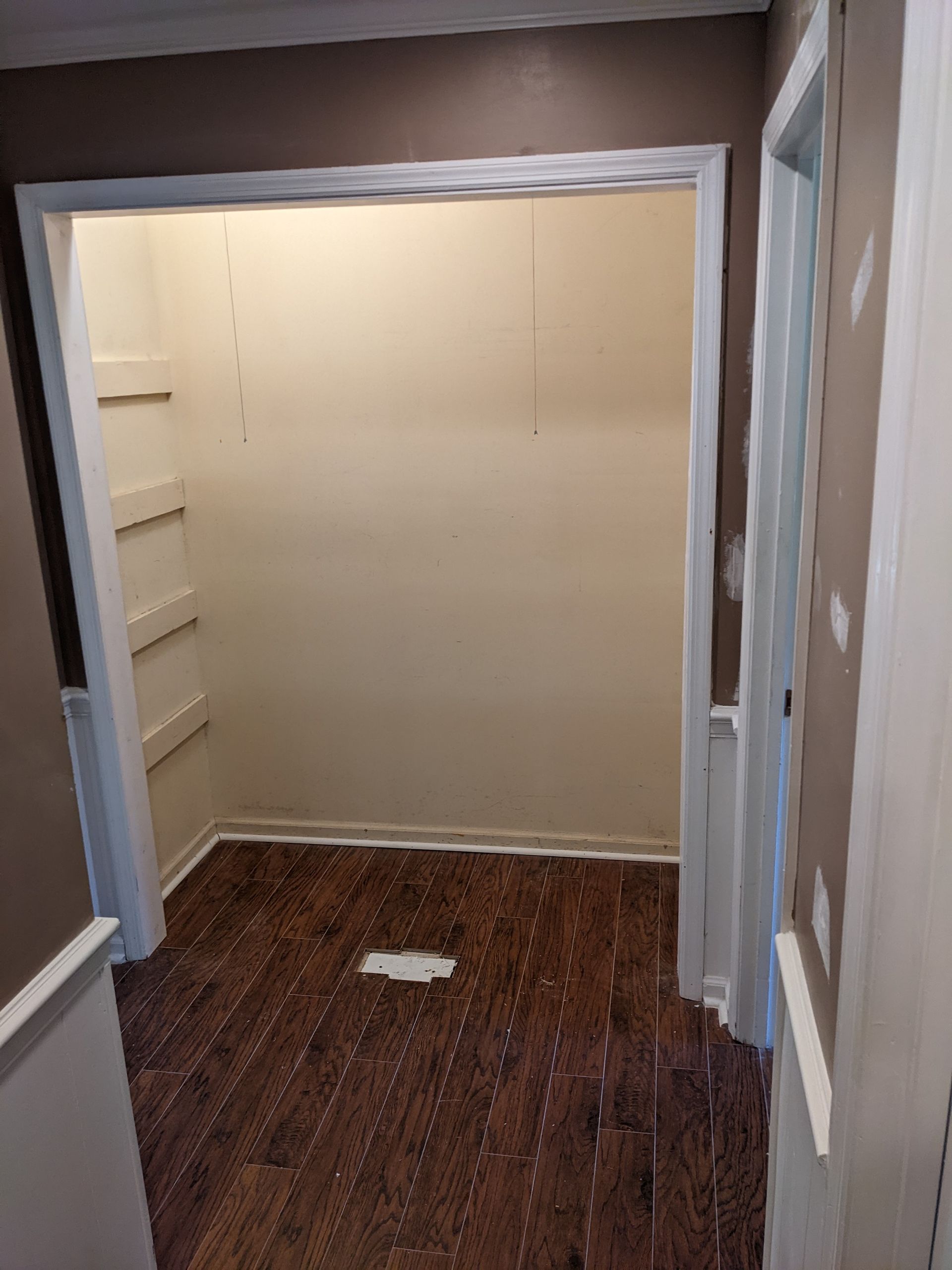 A closet with hardwood floors and white walls is being remodeled.