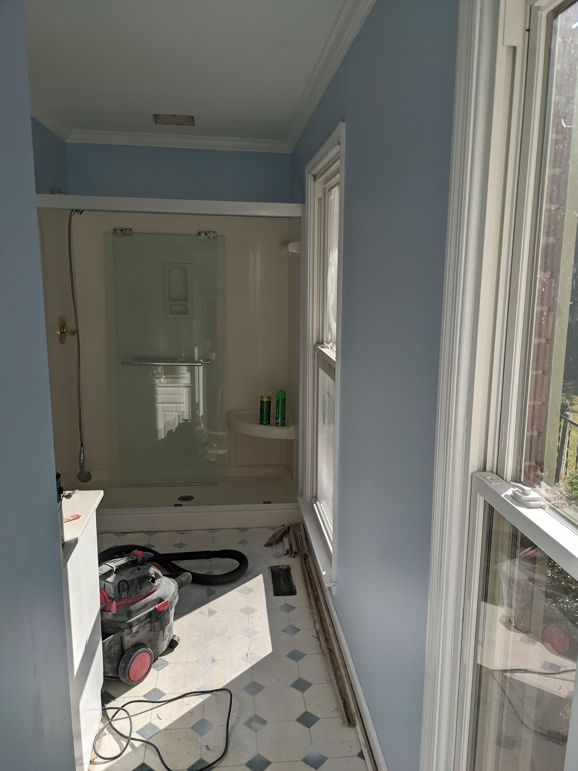 A bathroom with a walk in shower and a window.