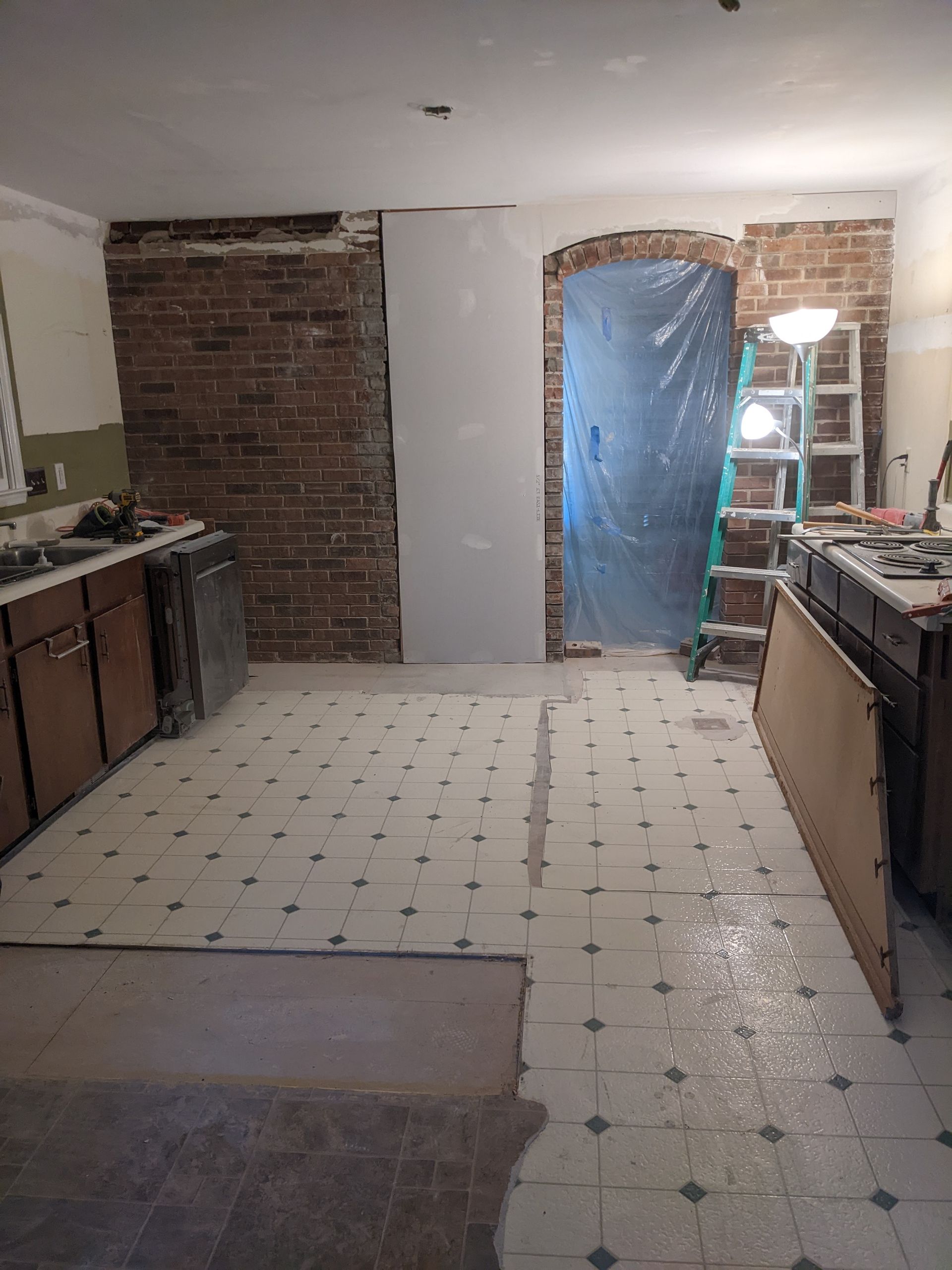 A kitchen under construction with a ladder and a brick wall.