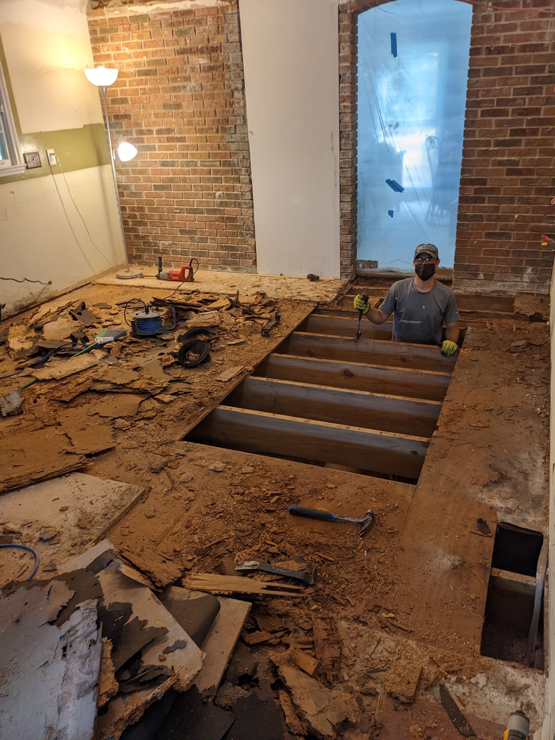 A man is sitting in a hole in the floor of a room.