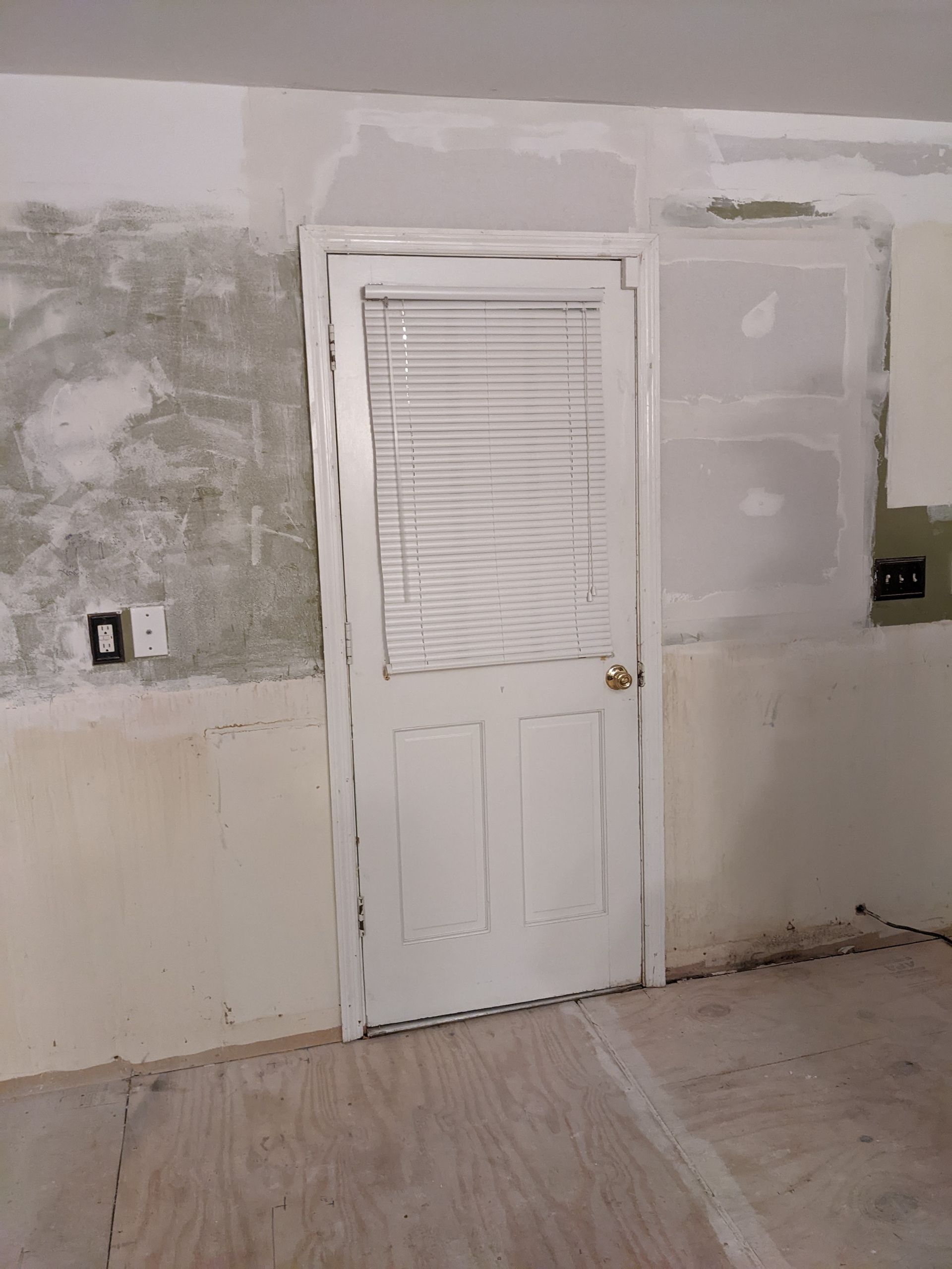 A white door with blinds on it is in a room.