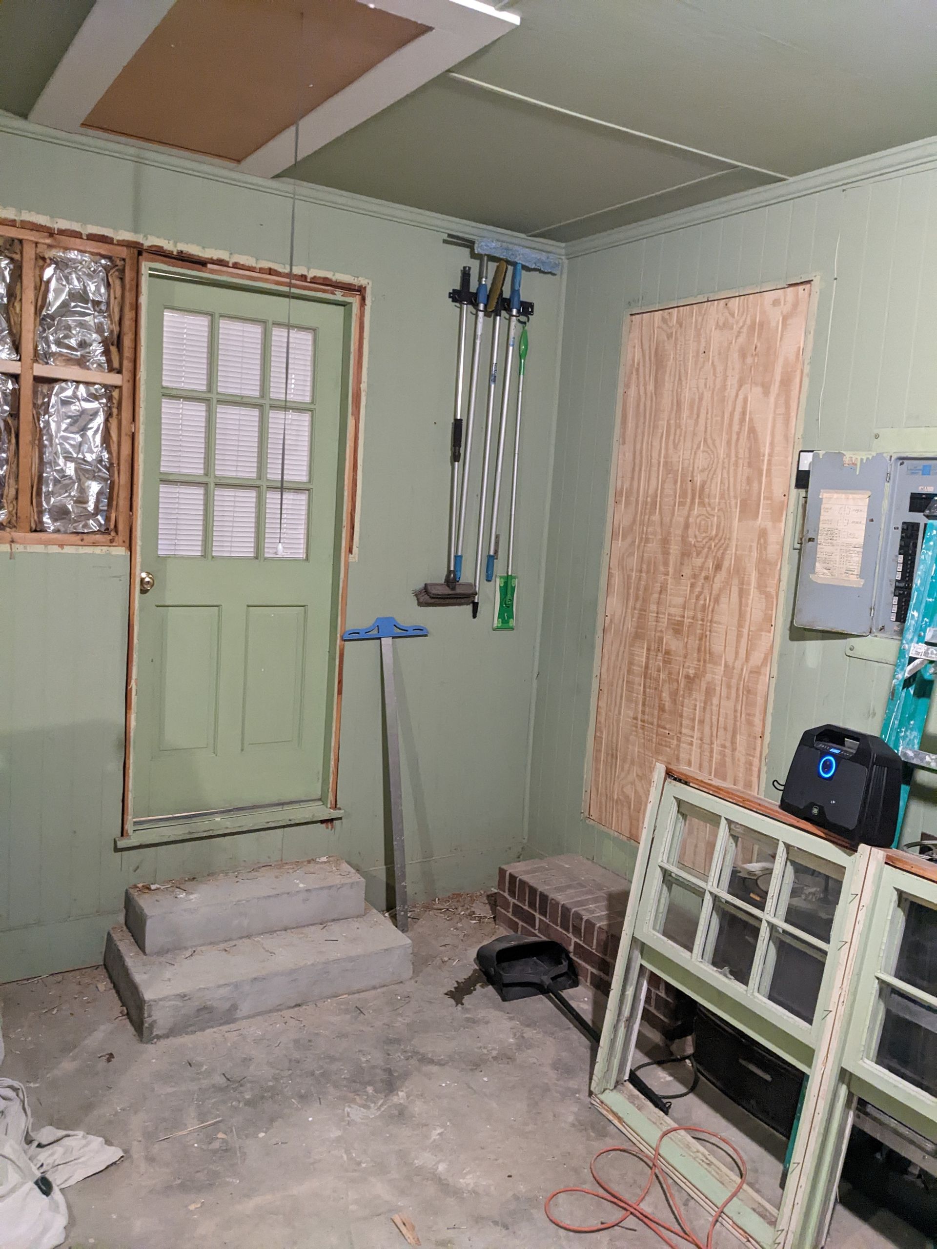 A room with a green door and a bunch of windows