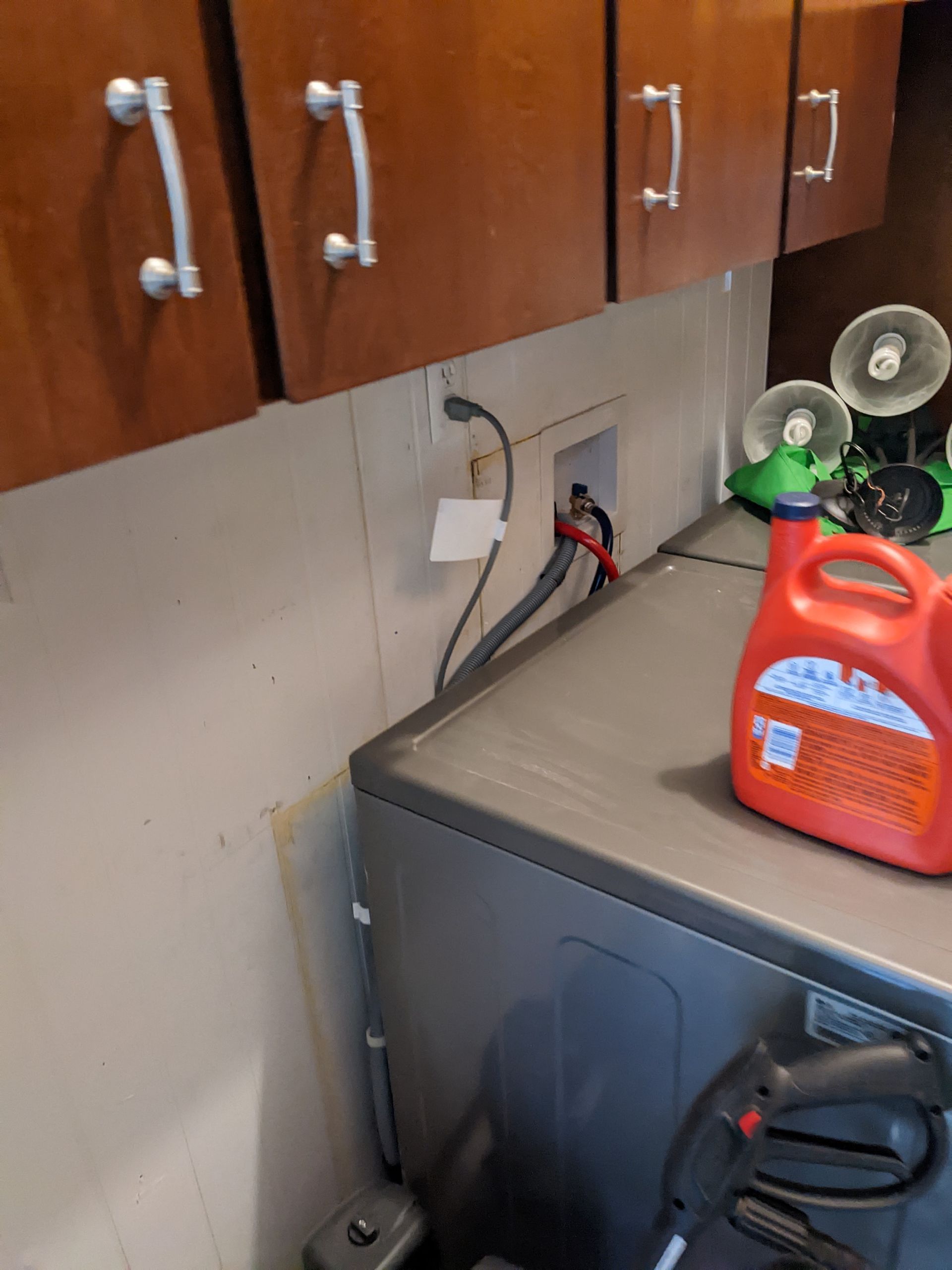 A bottle of laundry detergent is sitting on top of a washing machine.