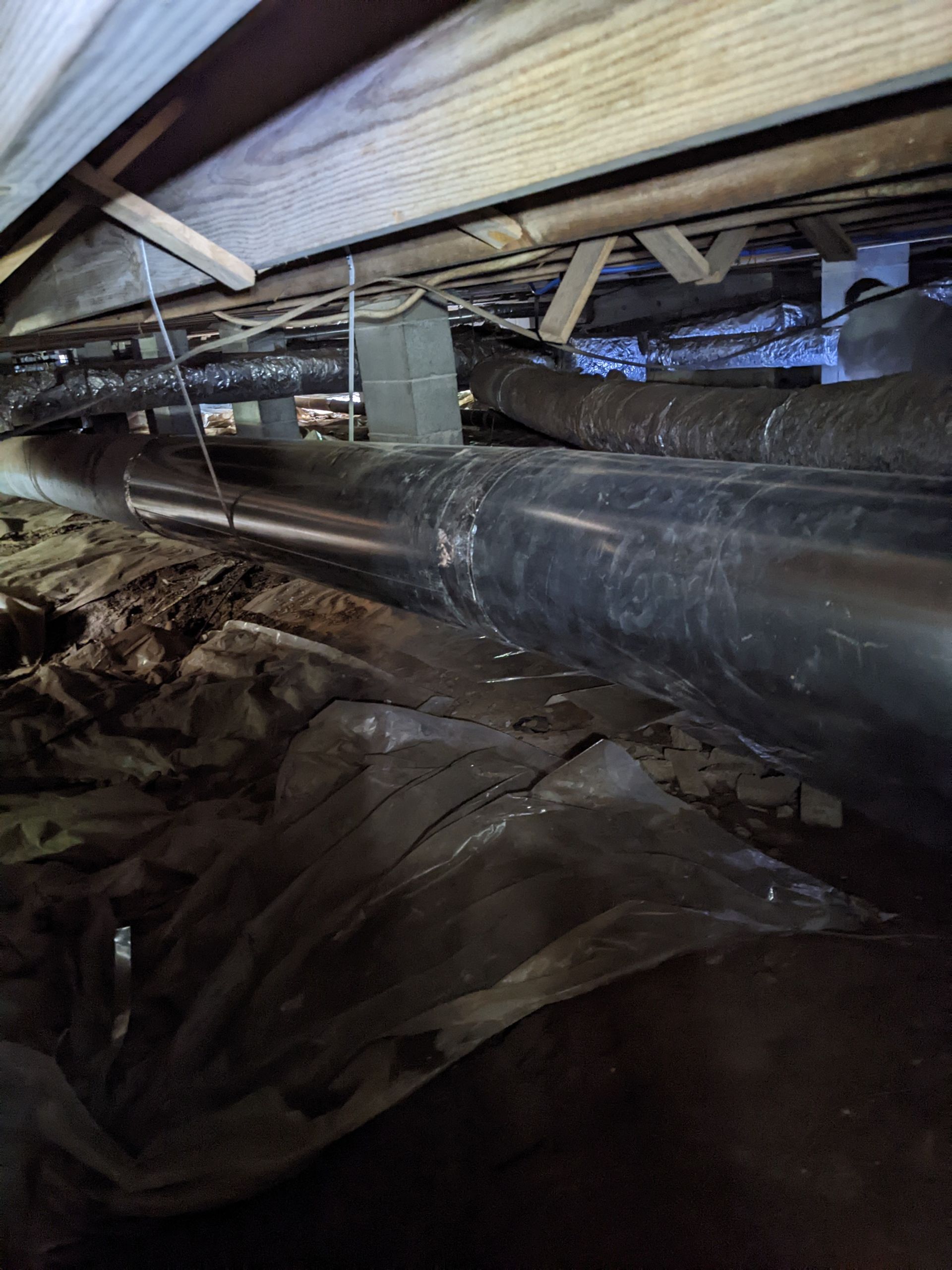 There are a lot of pipes in the crawl space of a house.
