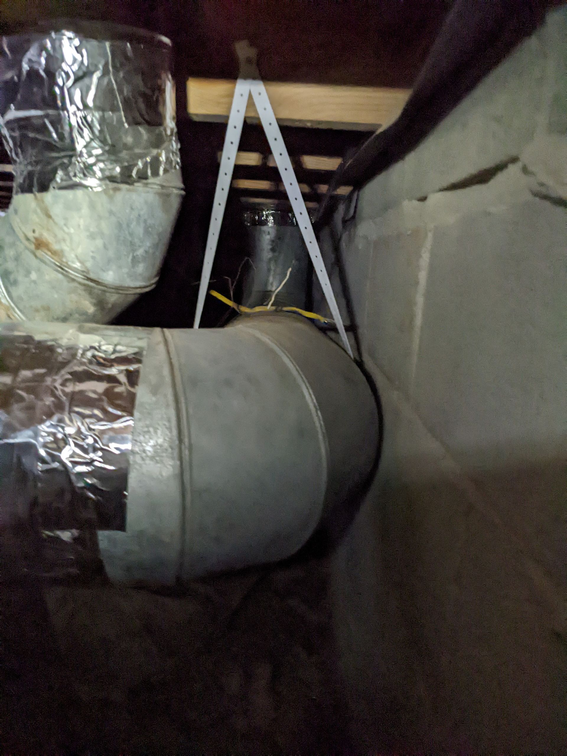 A ladder is hanging from the ceiling next to a metal pipe.