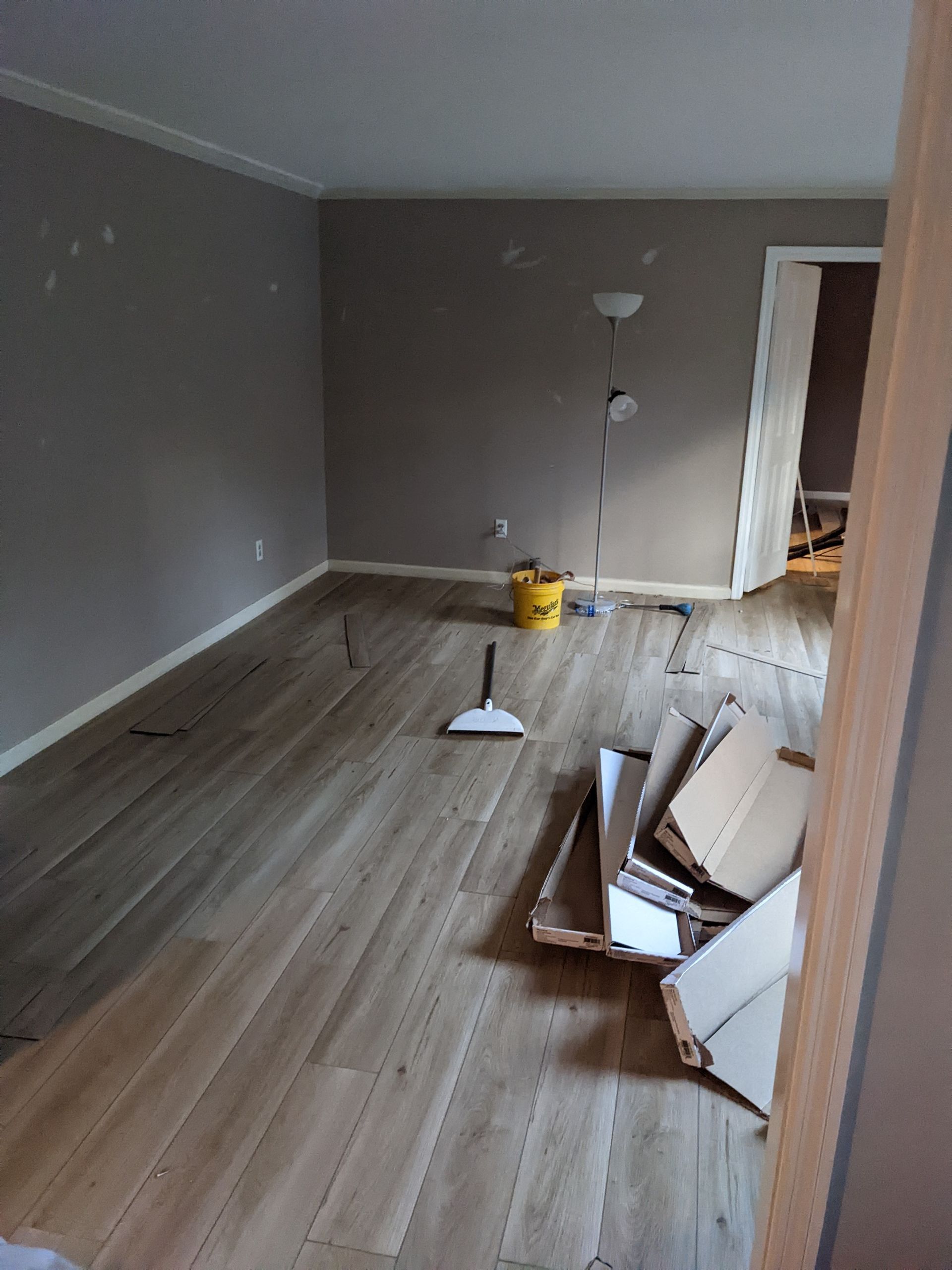 A living room with a wooden floor and boxes on the floor.