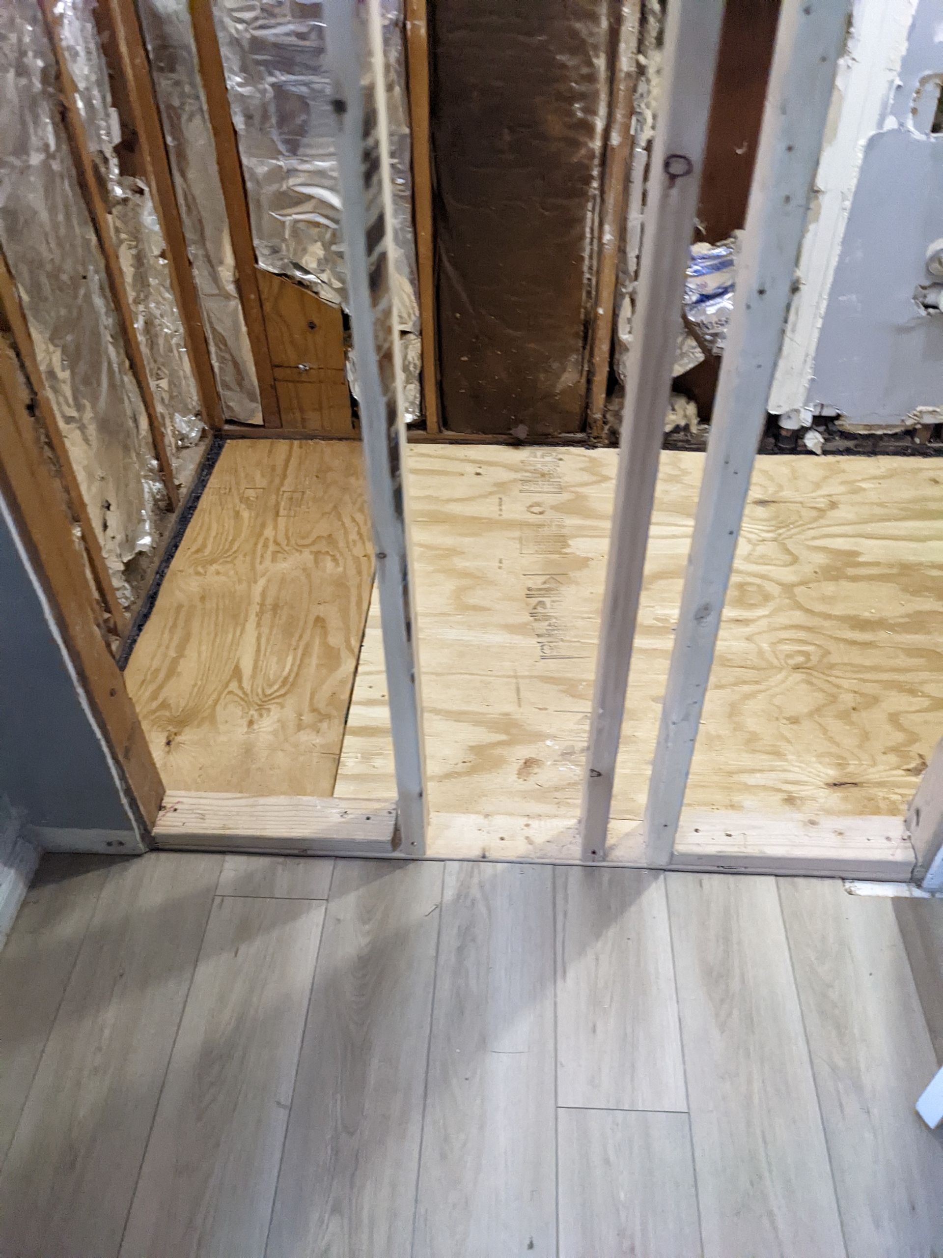 A bathroom with a wooden floor and a wooden wall.