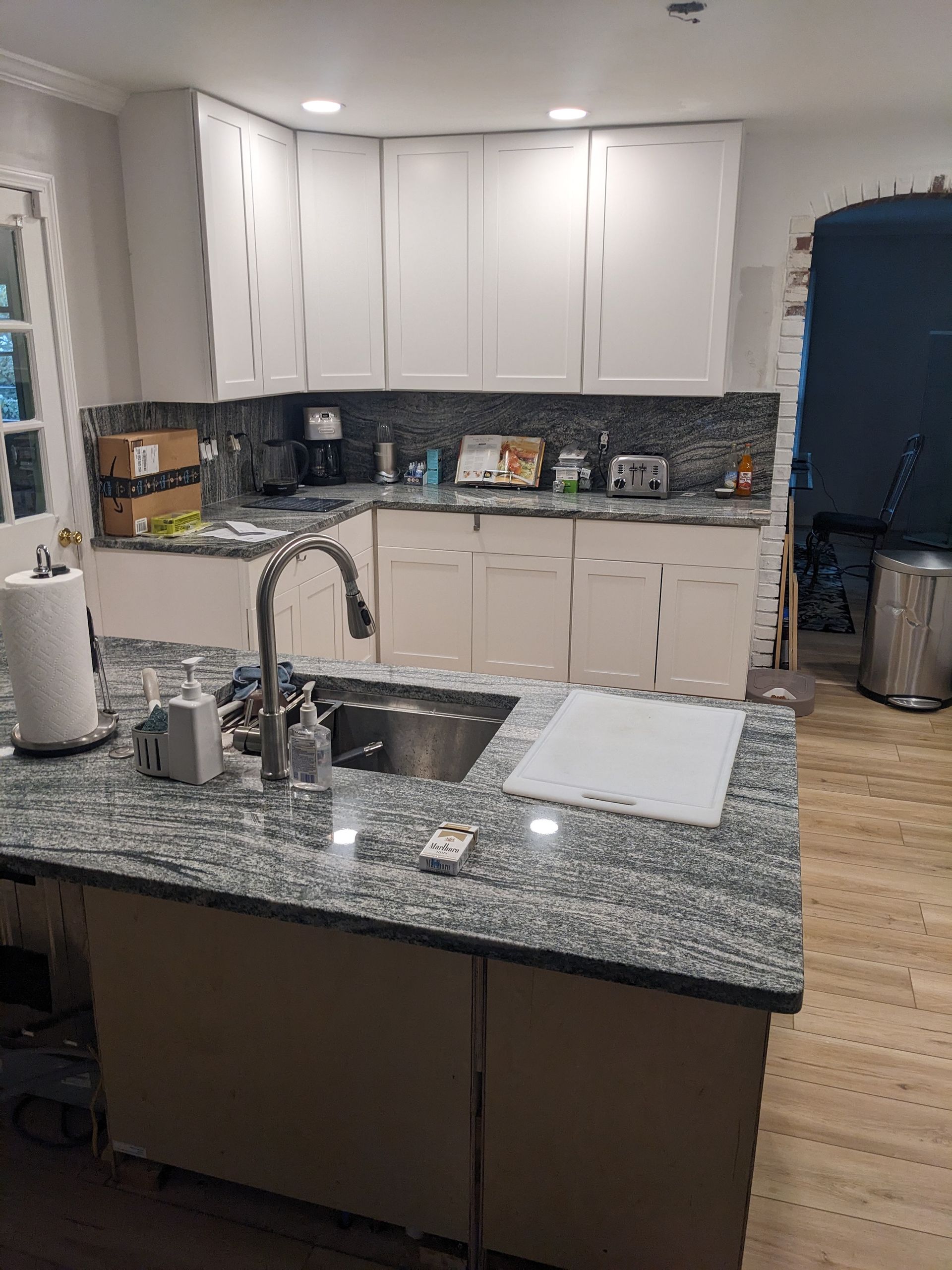 A kitchen with granite counter tops , white cabinets and a sink.