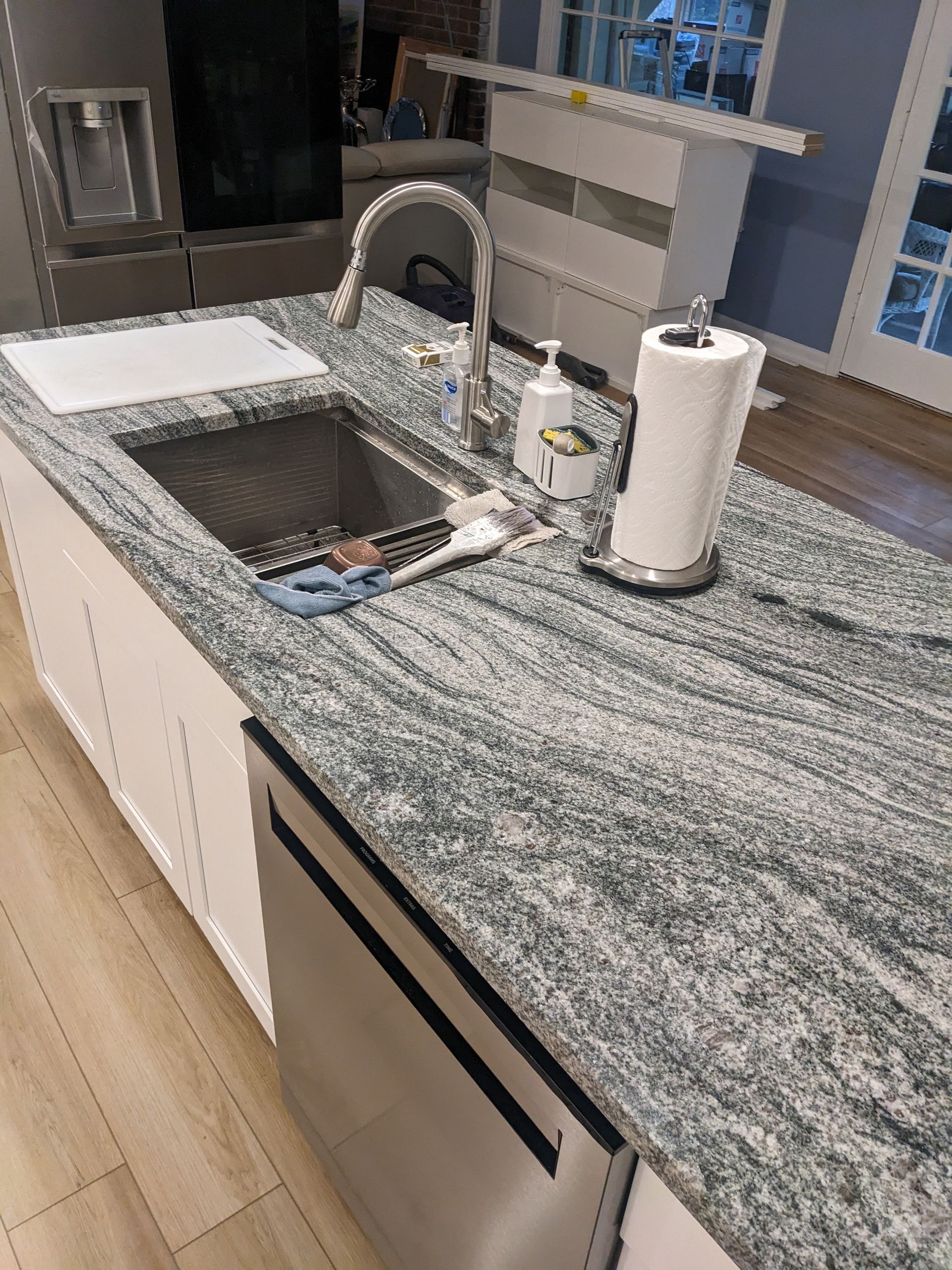 A kitchen with granite counter tops , a sink , a dishwasher , and a paper towel holder.