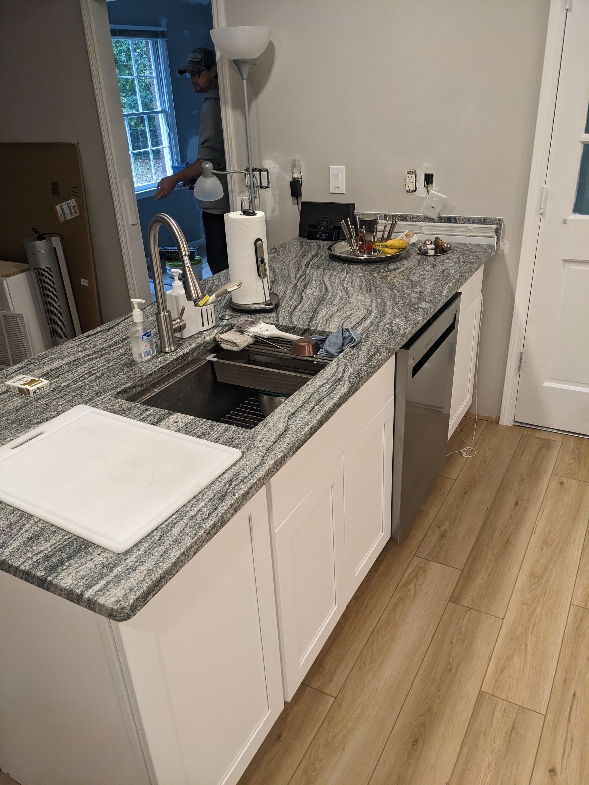 A kitchen with granite counter tops , white cabinets , a sink and a dishwasher.