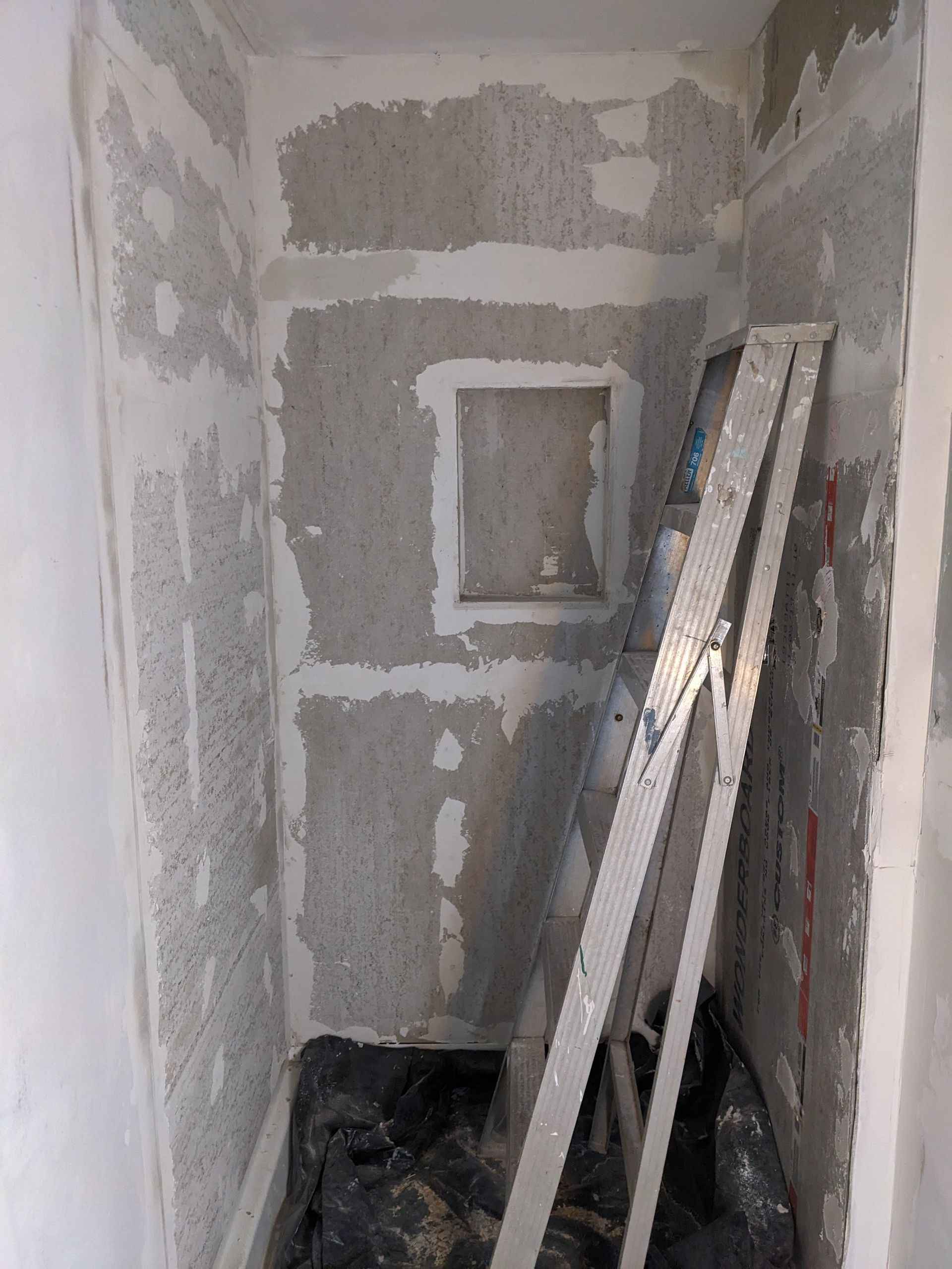 A ladder is leaning against a wall in a room under construction.