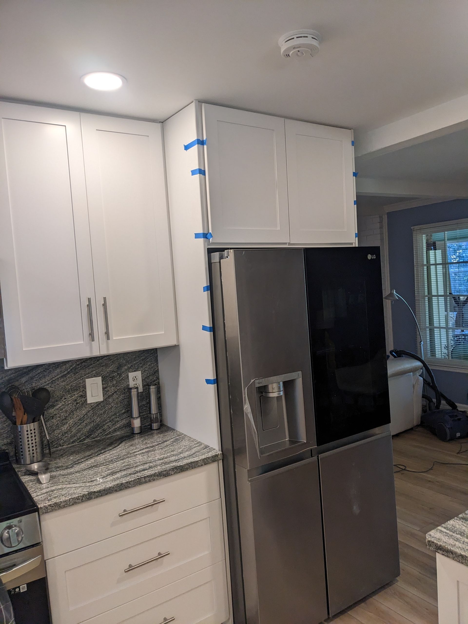 A kitchen with white cabinets and a stainless steel refrigerator.