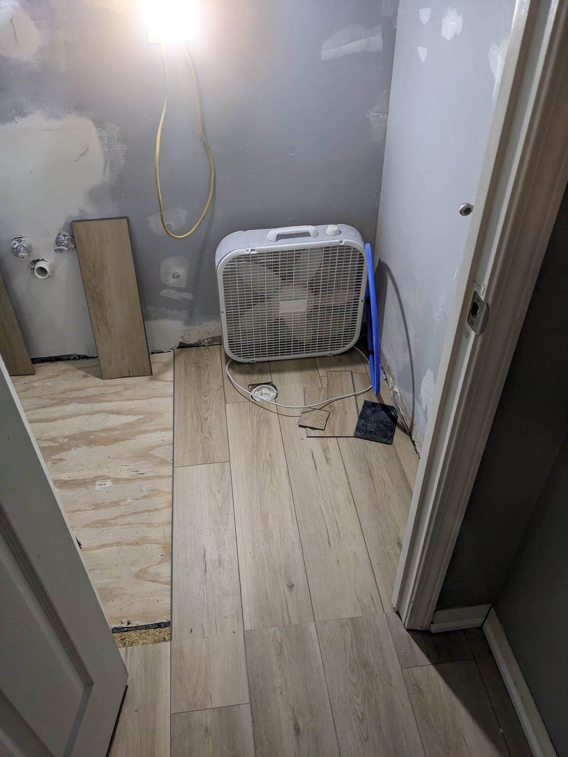 A fan is sitting on a wooden floor in a room.