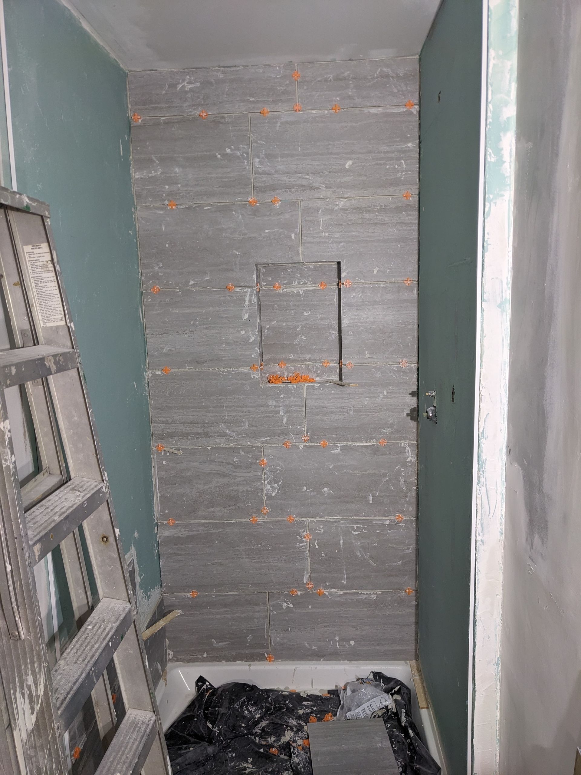 A bathroom under construction with a ladder and a shower stall.