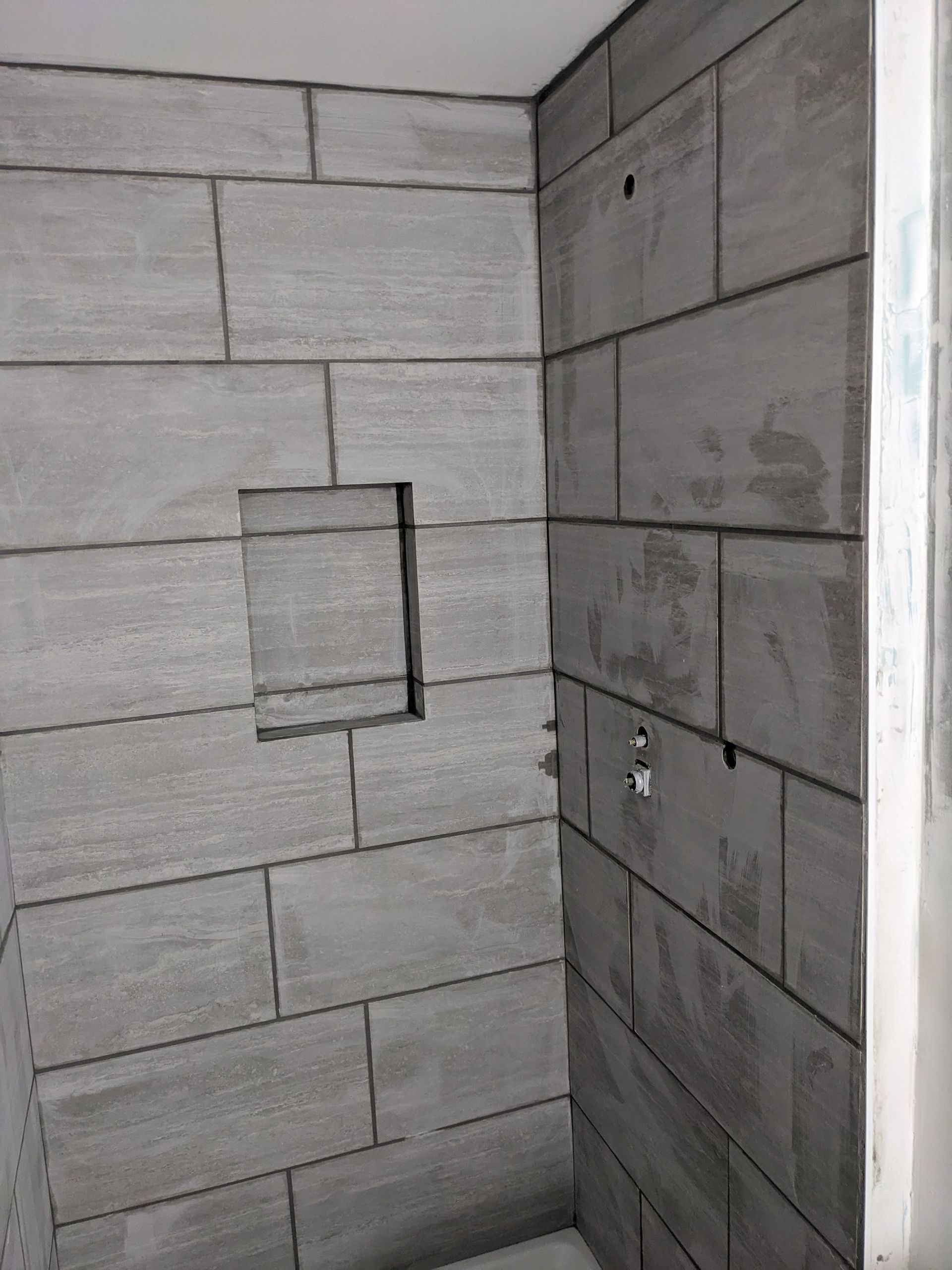 A corner of a bathroom with brick walls and a hole in the wall