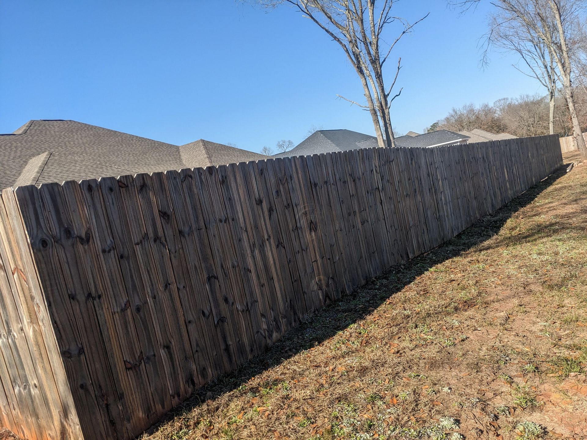 A long wooden fence is sitting on top of a grassy hill.
