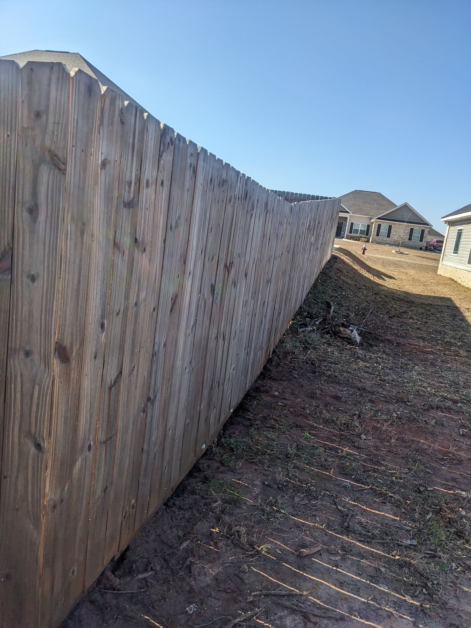 A long wooden fence is sitting in the middle of a dirt field.