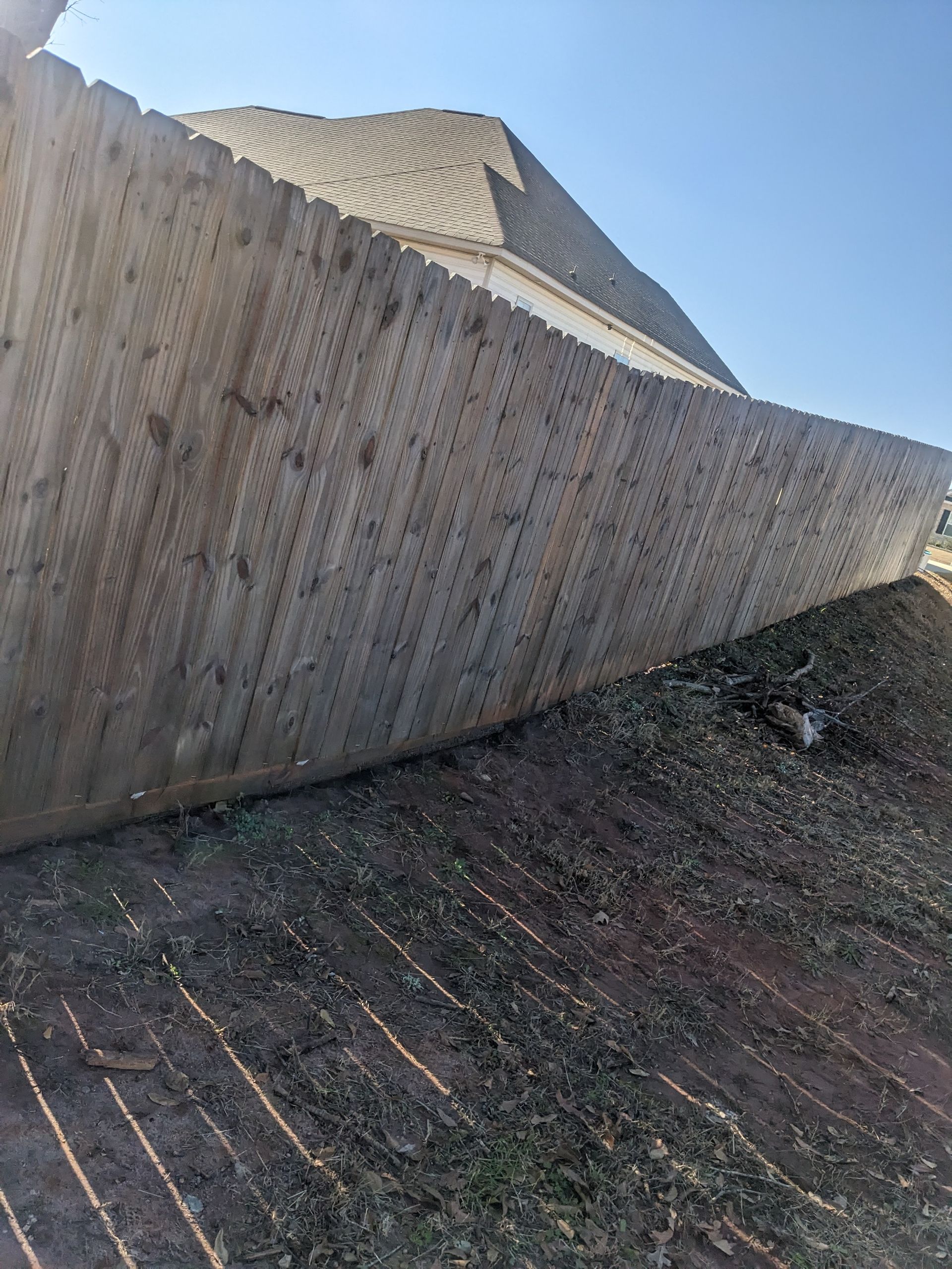 A wooden fence is sitting on top of a pile of leaves next to a house.