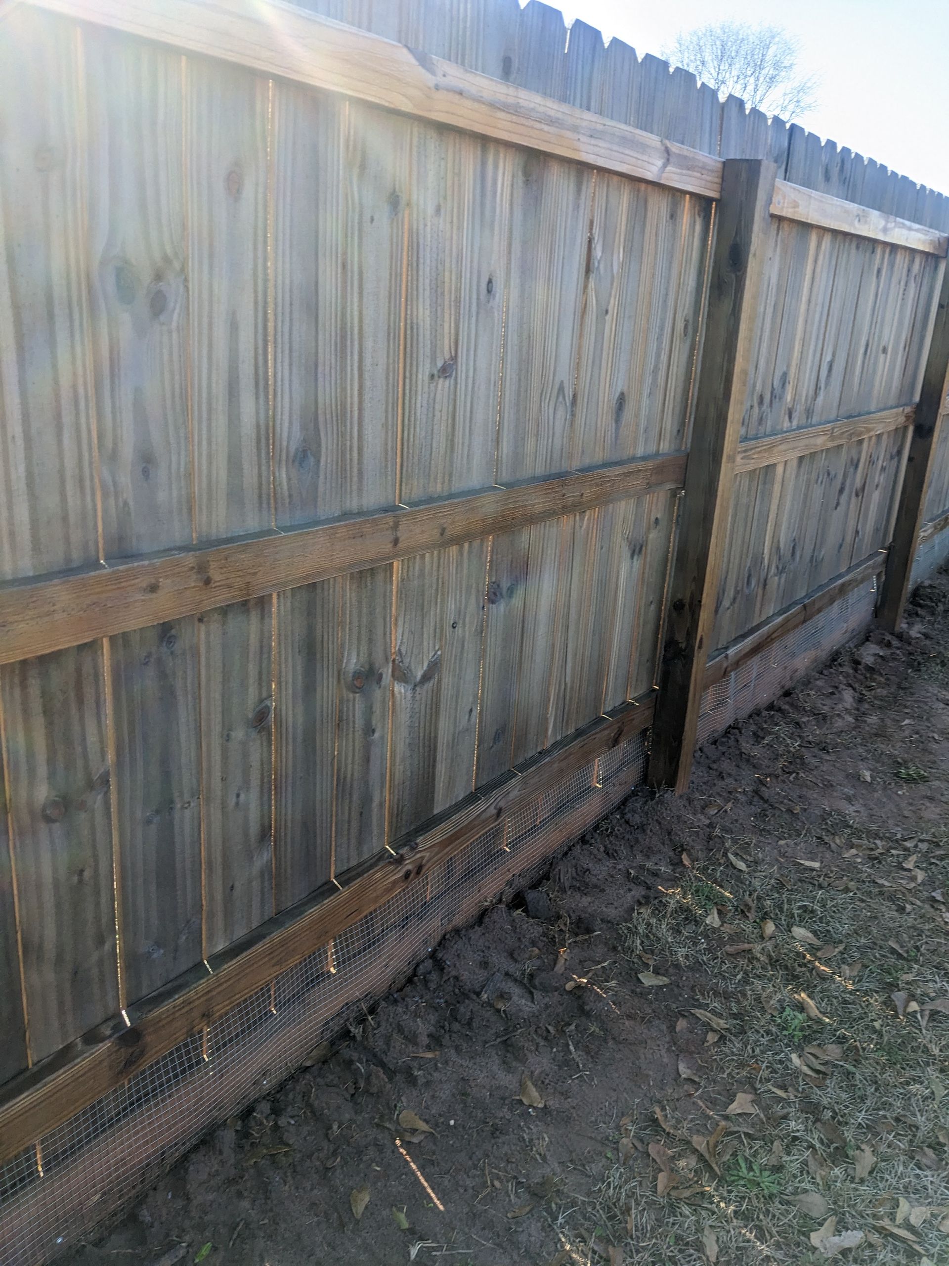 A wooden fence is sitting on top of a dirt field.