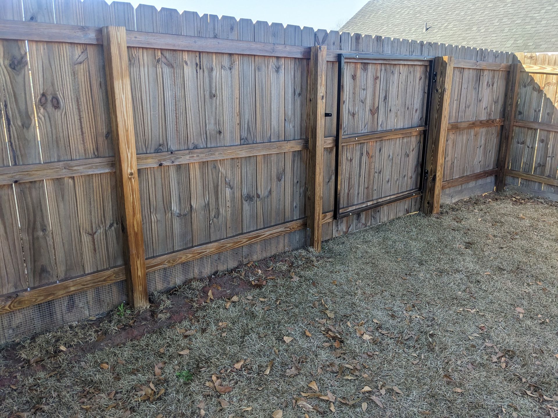 A wooden fence with a gate in the backyard.