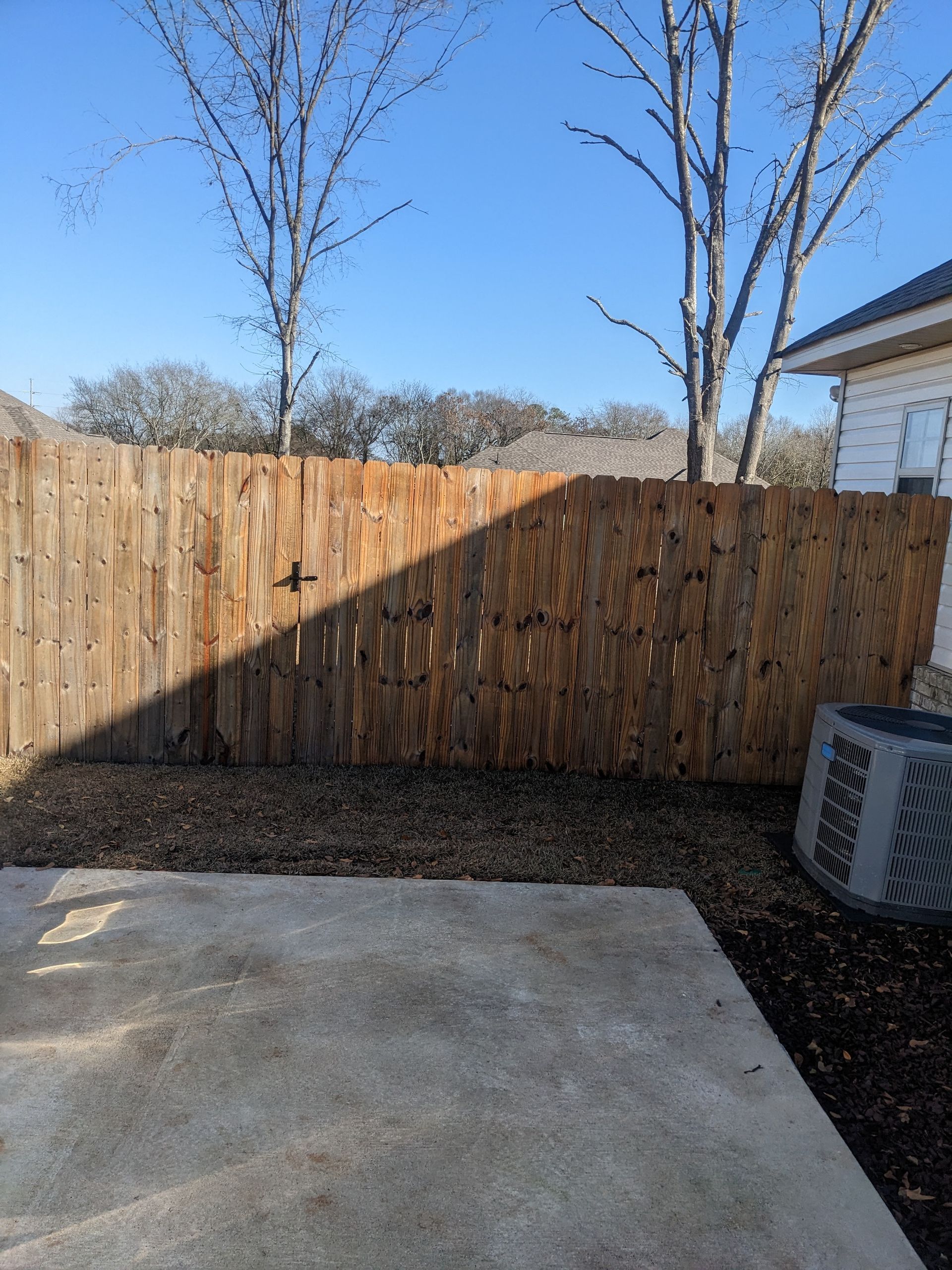 A wooden fence is in the backyard of a house.