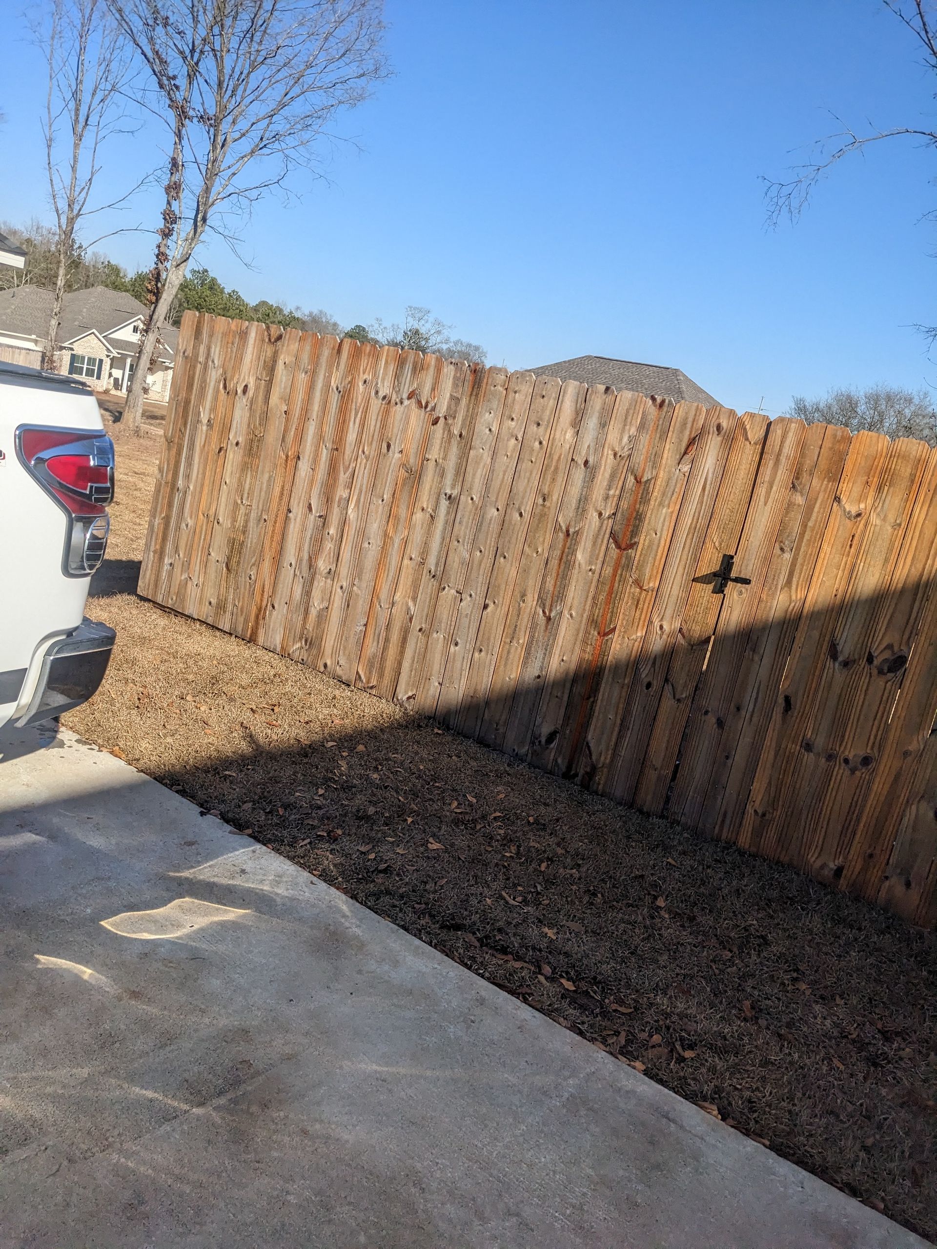 A car is parked in front of a wooden fence.