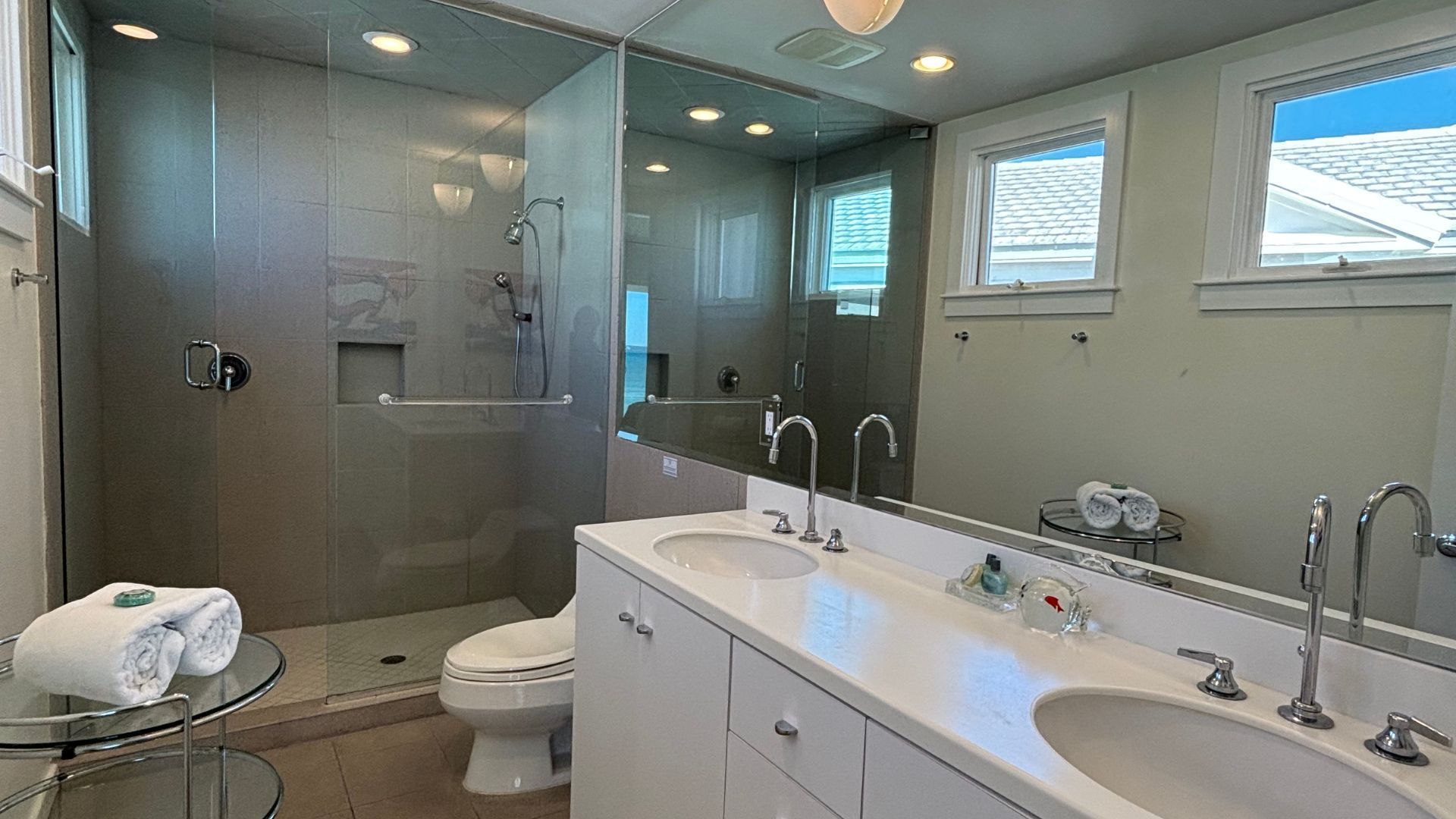 A bathroom with two sinks , a toilet and a walk in shower.