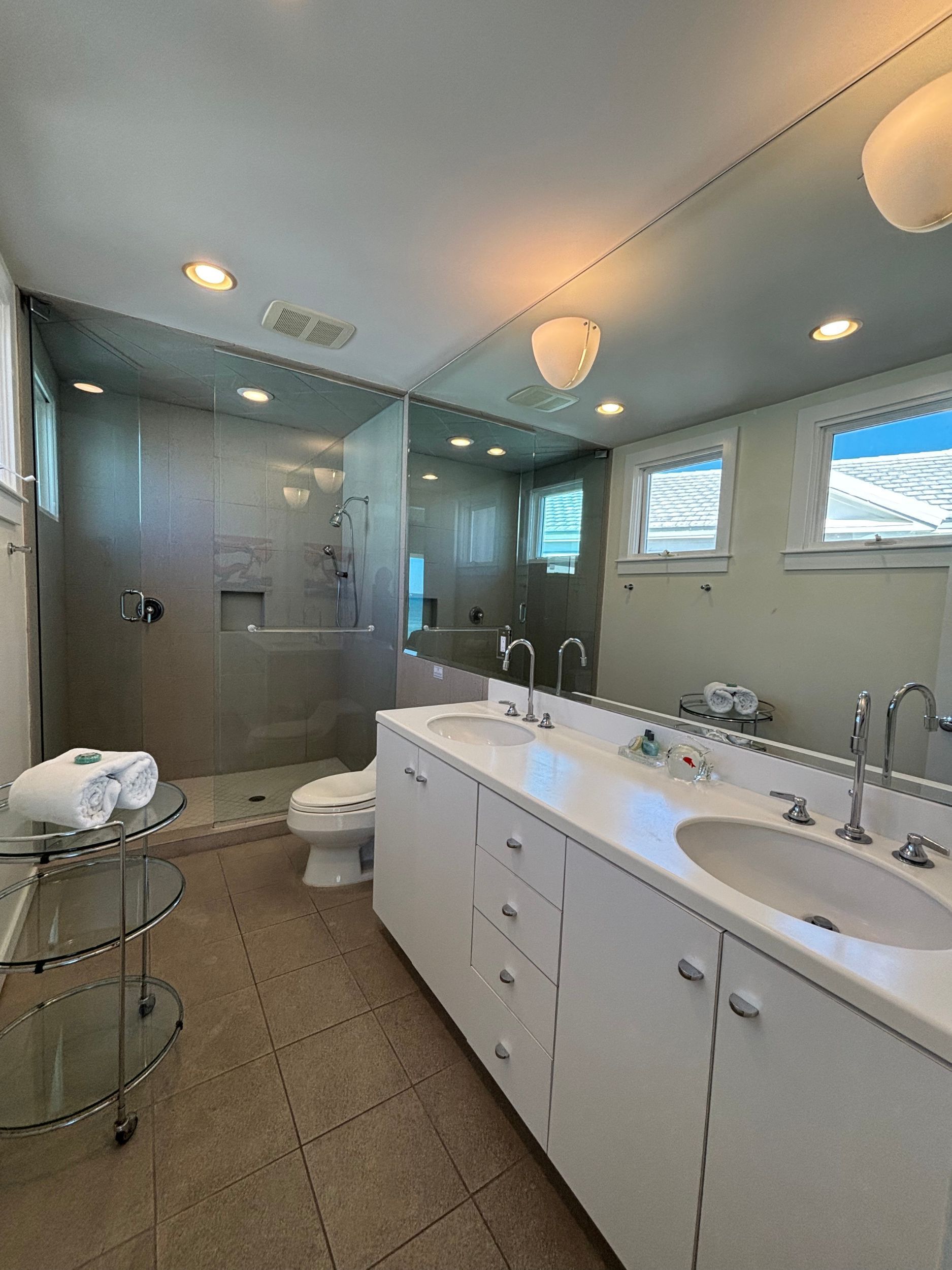 A bathroom with two sinks , a toilet , and a walk in shower.