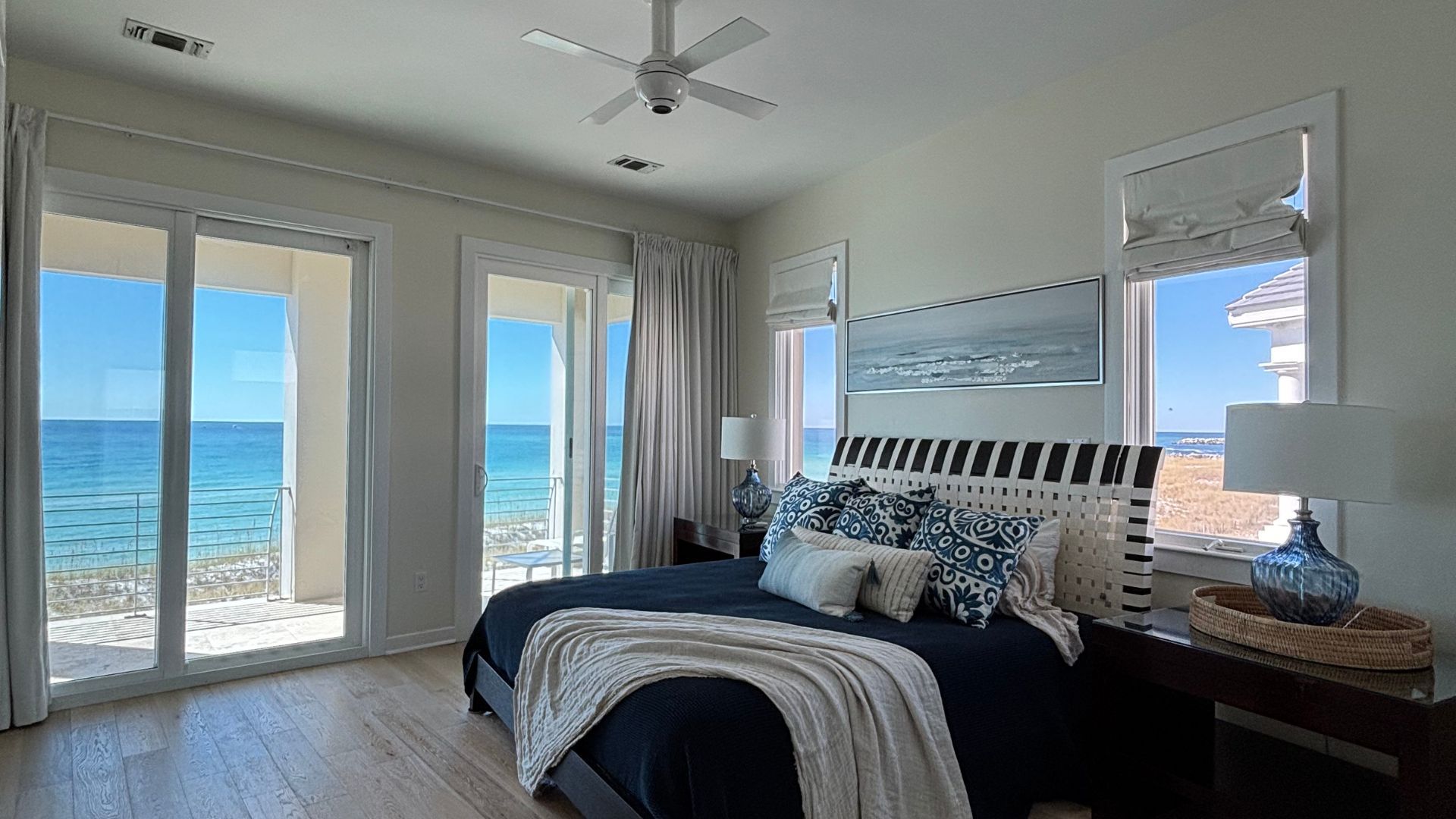 A bedroom with a large bed and a ceiling fan overlooking the ocean.