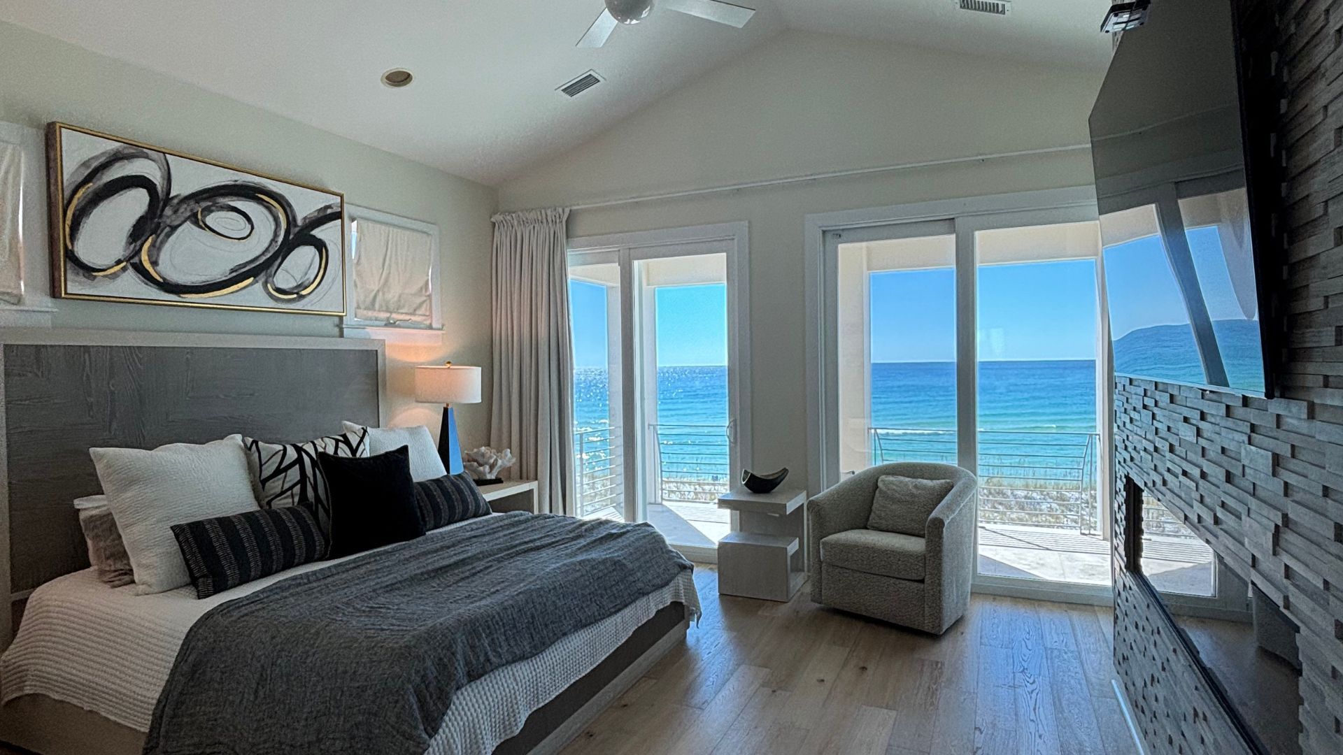 There is a large bed in the middle of the room with a view of the ocean.