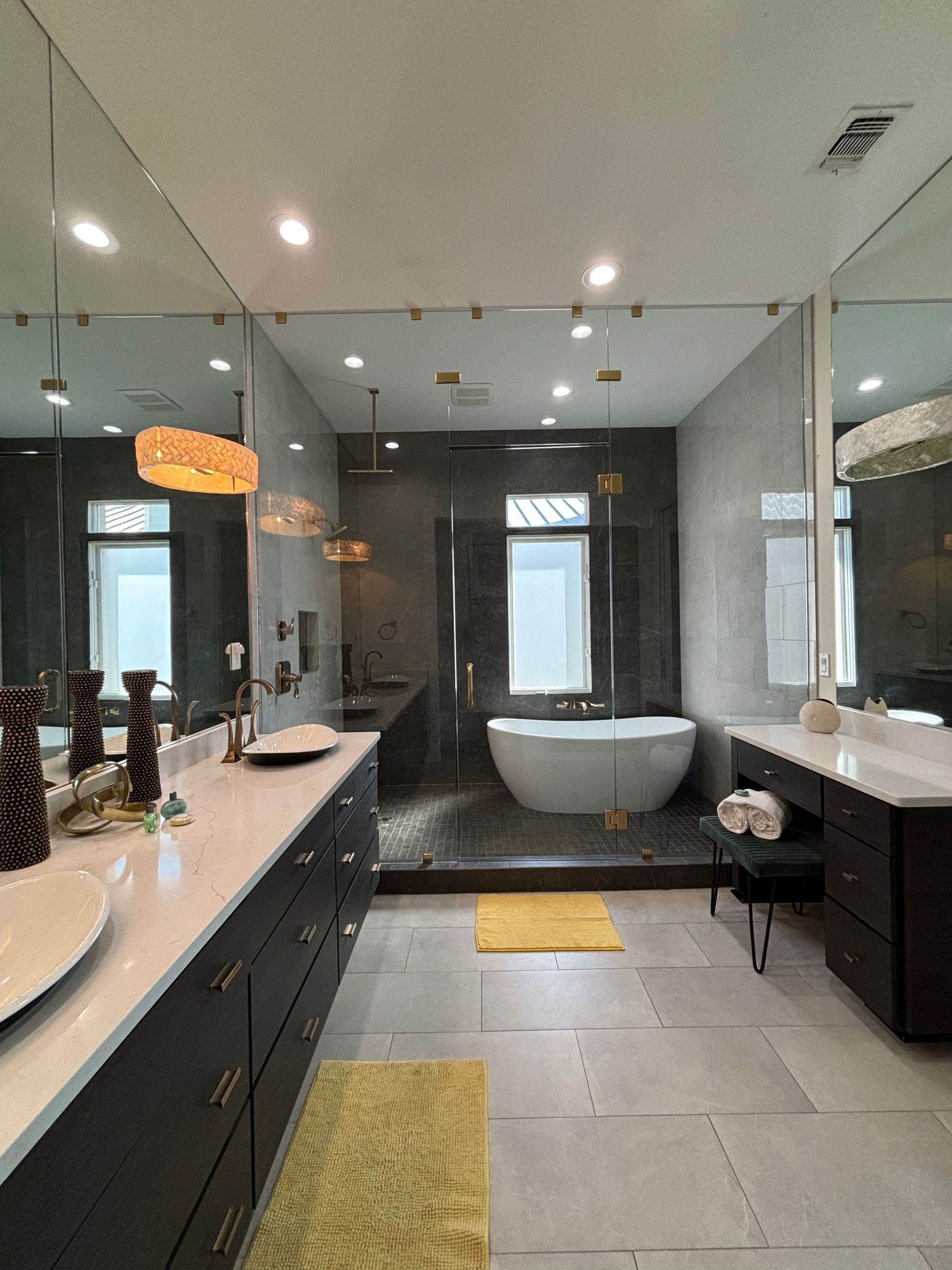 A bathroom with two sinks , a tub , and a large mirror.