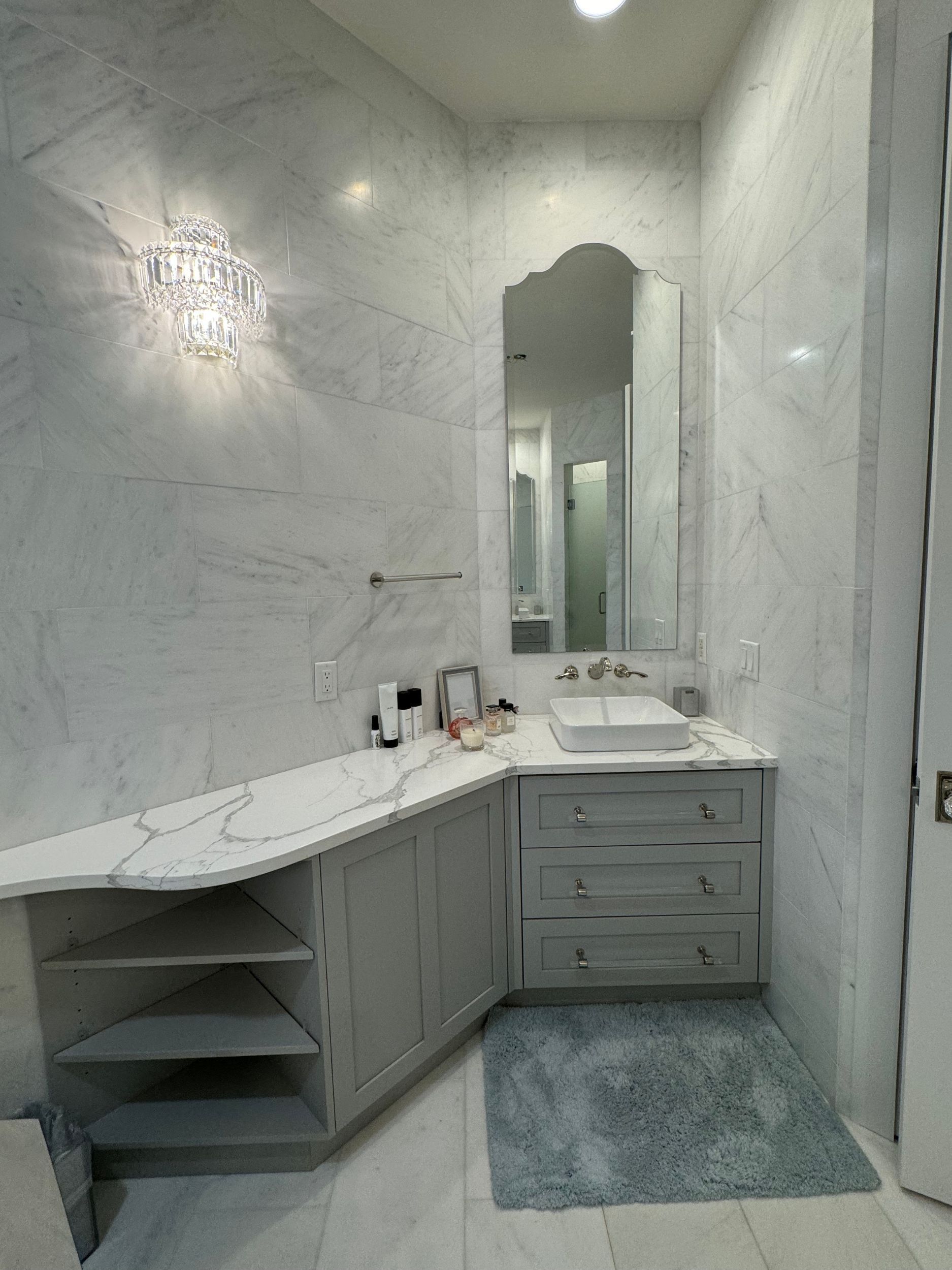 A bathroom with marble walls , a sink , and a mirror.