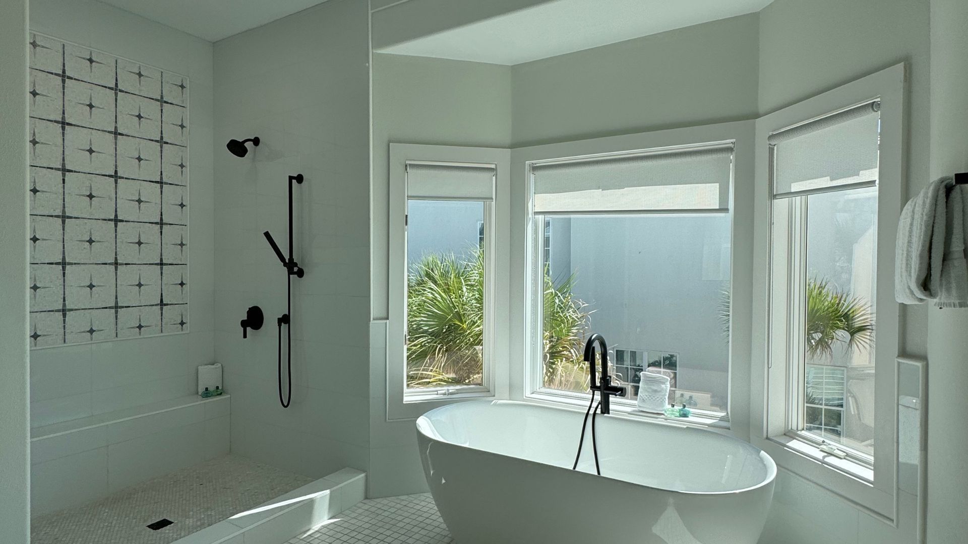 A bathroom with a tub , shower , mirror and window.