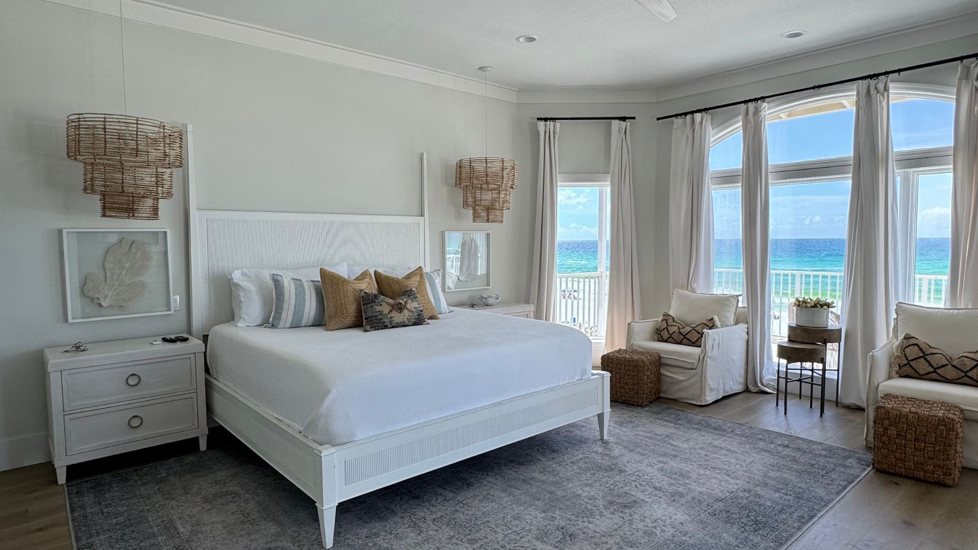 There is a large bed in the middle of the room with a view of the ocean.