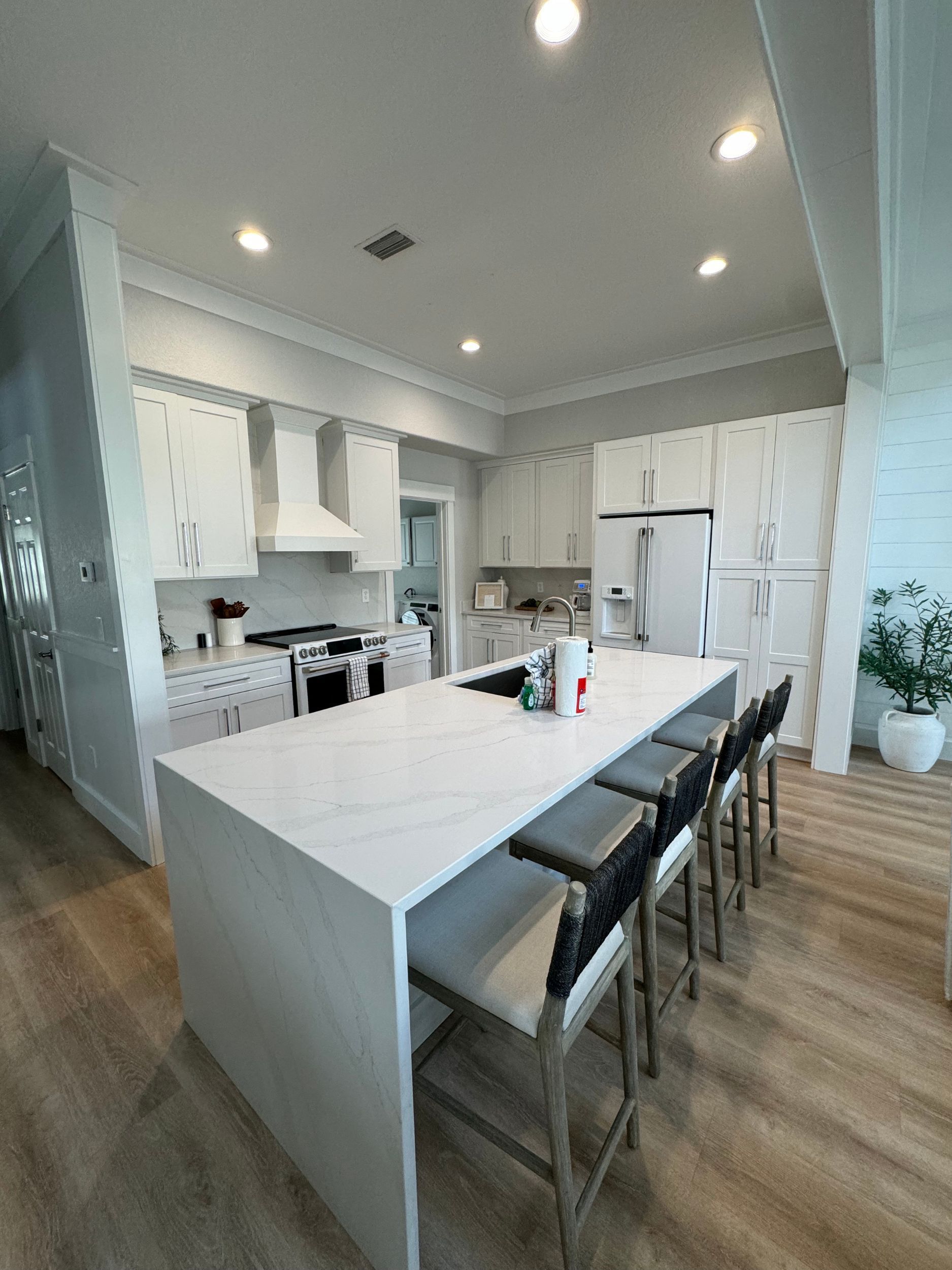 A kitchen with a large island and stools in it.