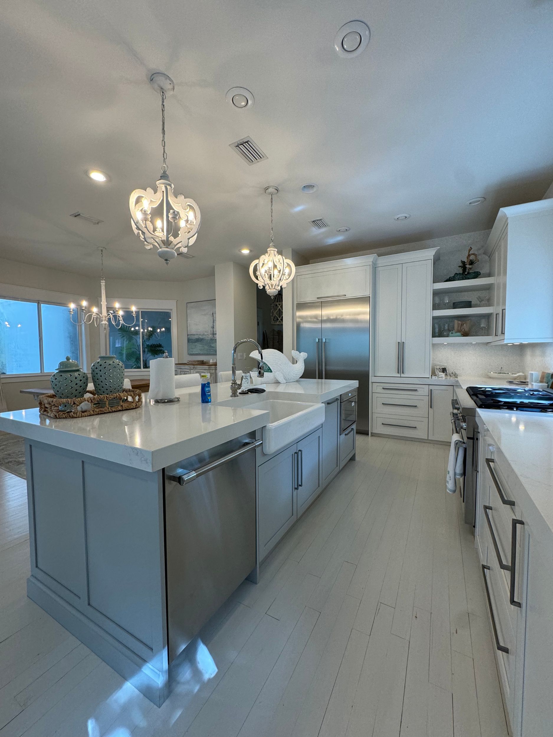 A kitchen with white cabinets , stainless steel appliances , and a large island.