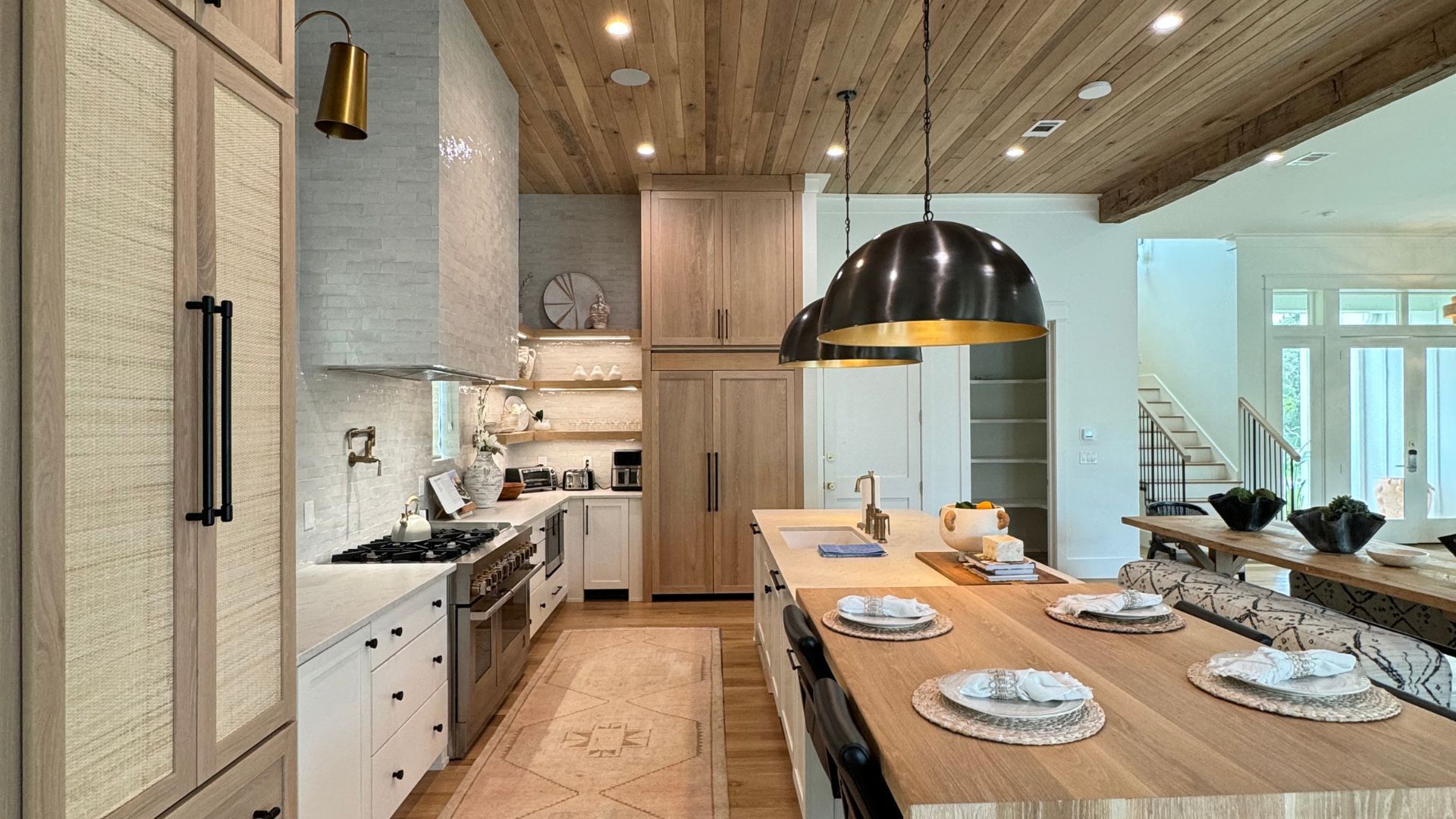 A kitchen with a long wooden table and stainless steel appliances.