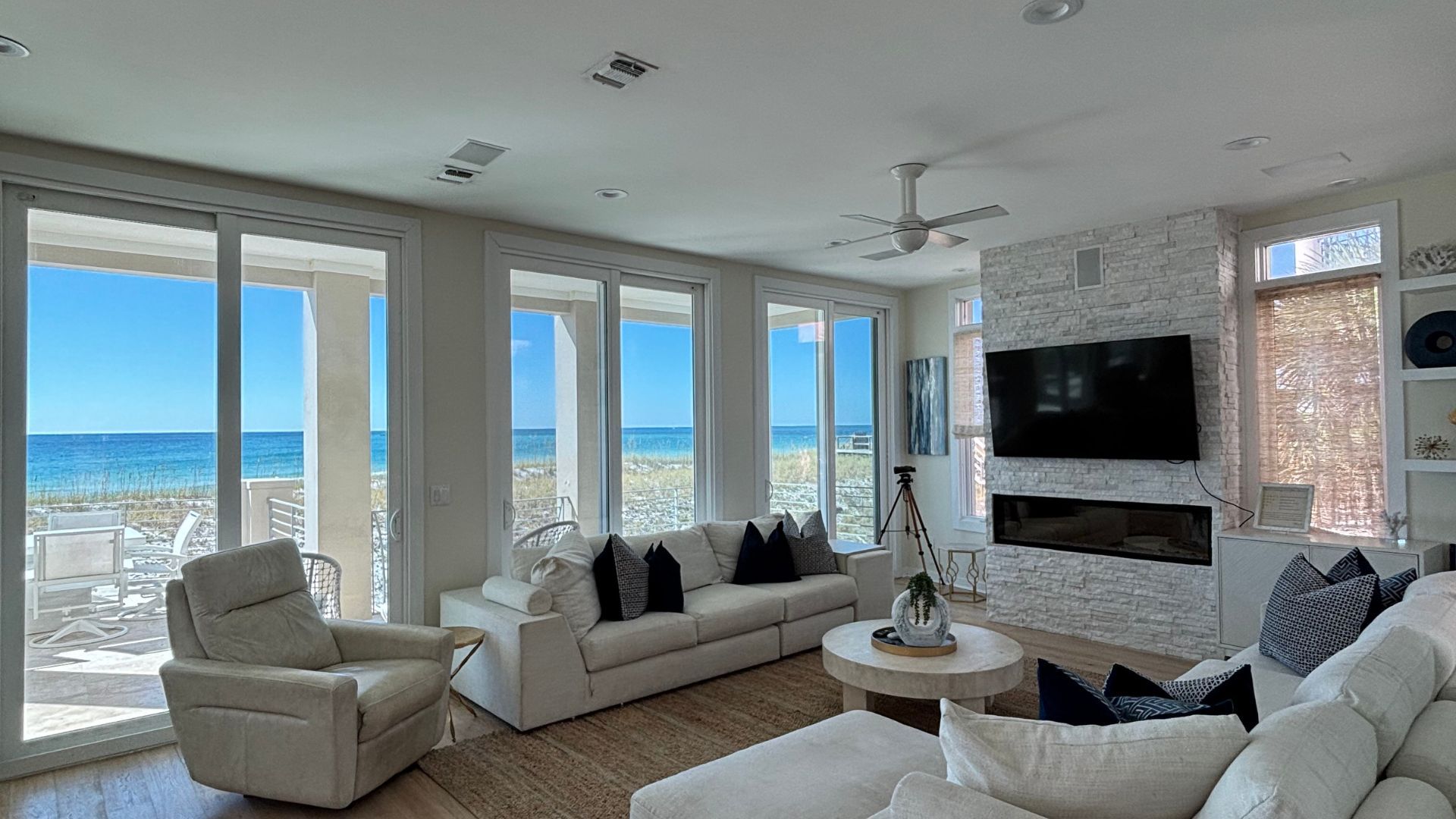 A living room filled with furniture and a television with a view of the ocean.
