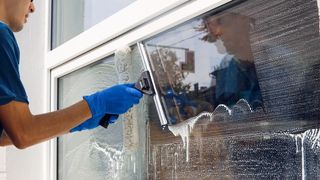 A man is cleaning a window with a squeegee.