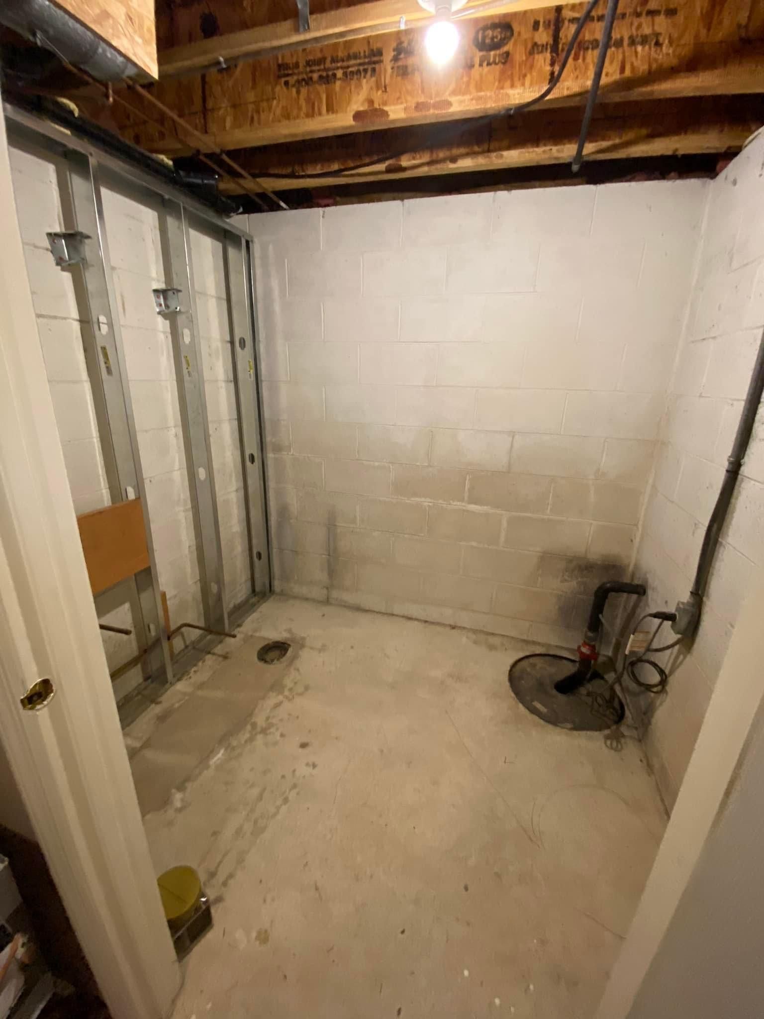 A basement with white walls and a drain in the floor.