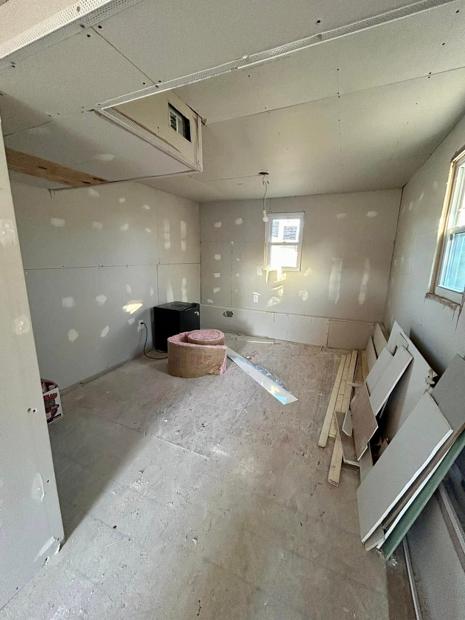 A room with drywall on the walls and a window.