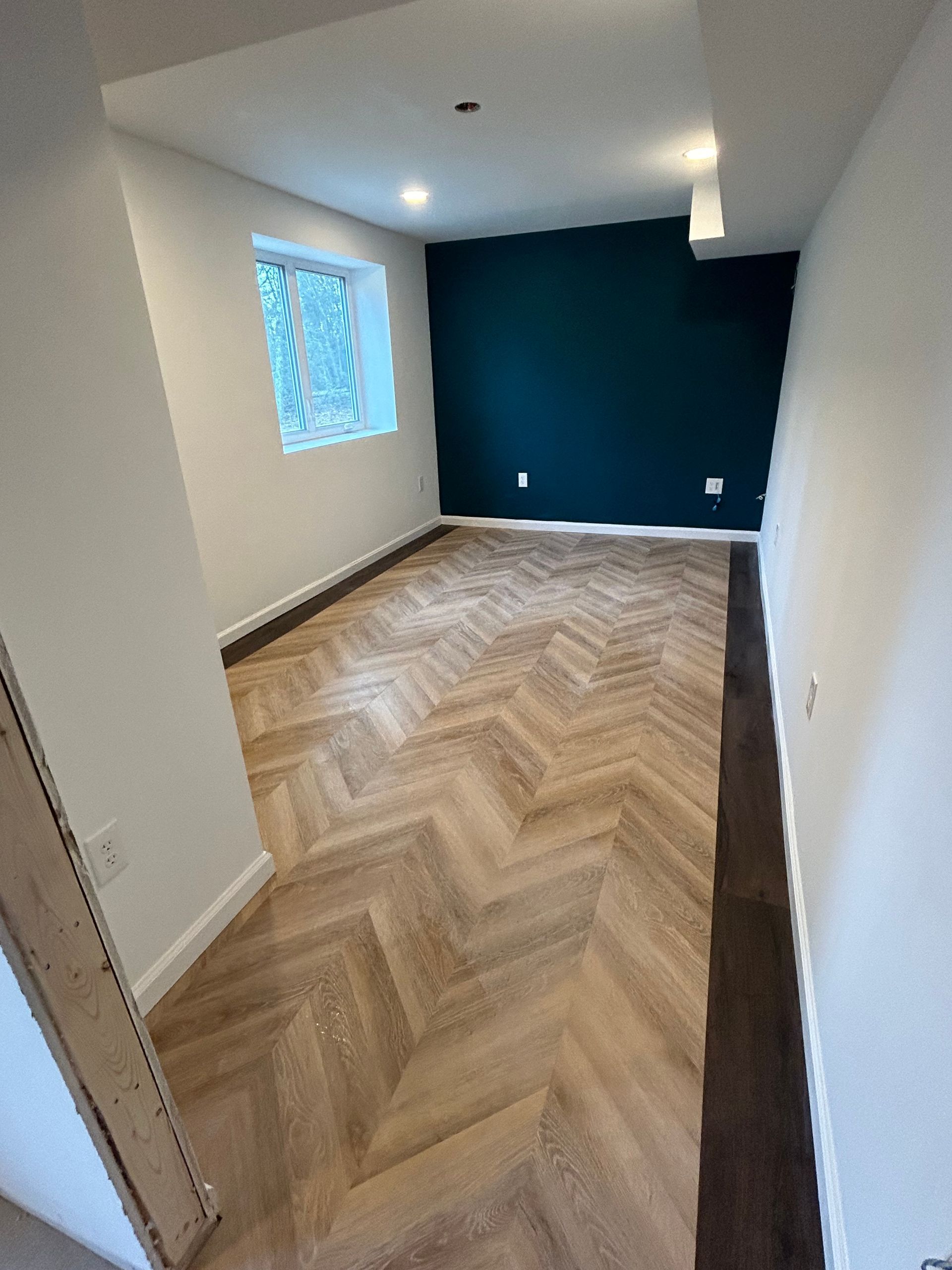 A room with a herringbone floor and a green wall