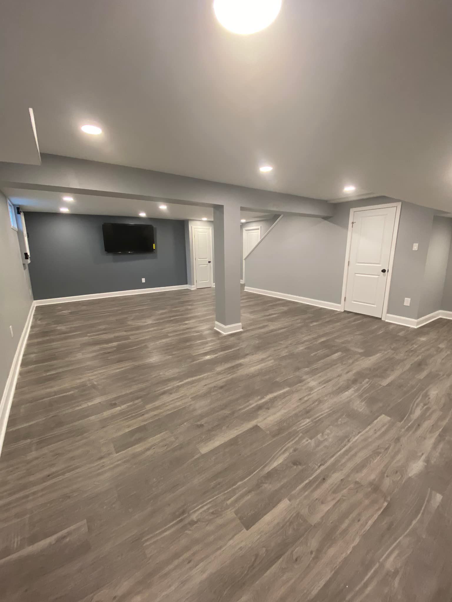 A large empty basement with hardwood floors and a flat screen tv.